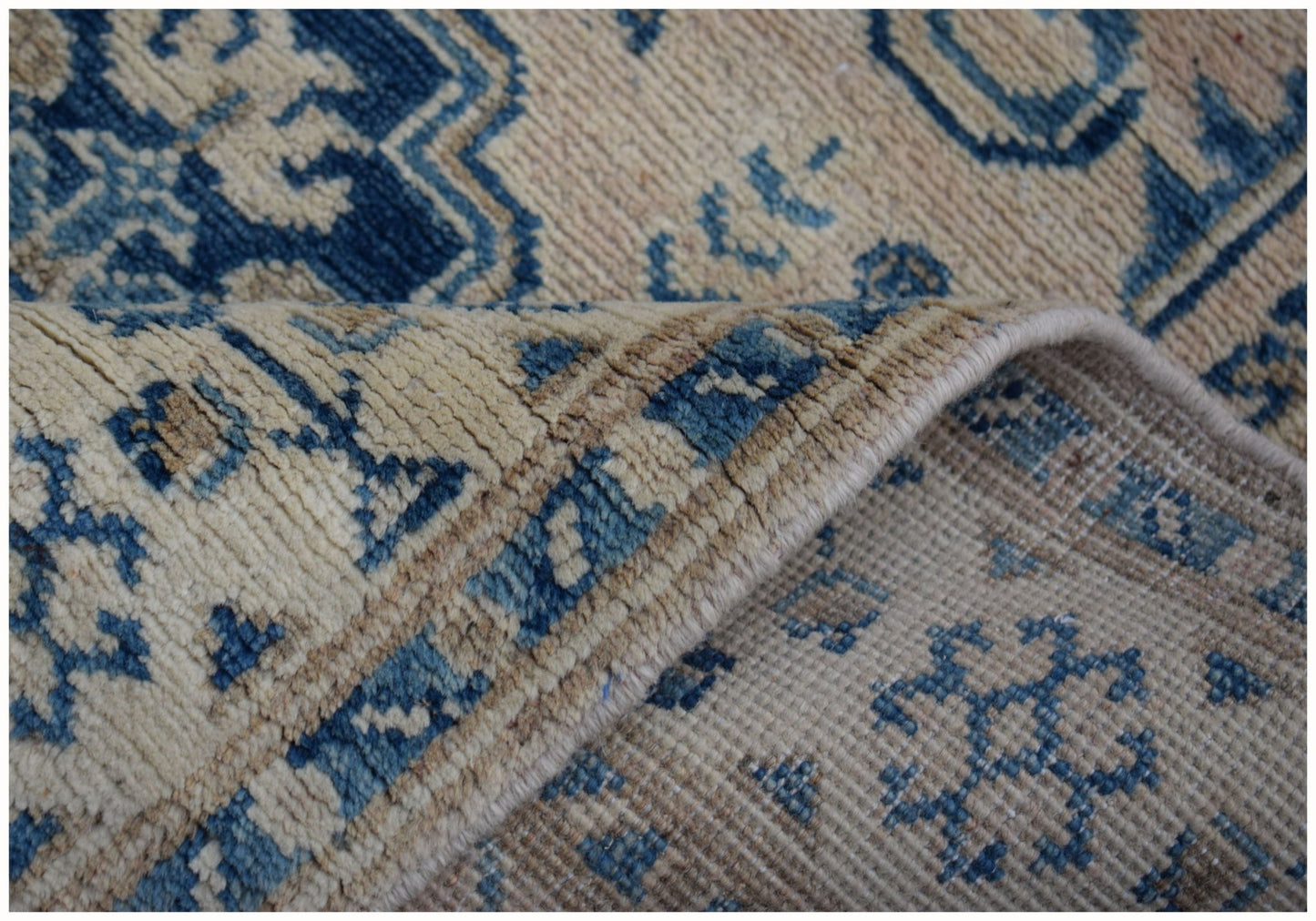 A close-up of a handmade Afghan Kazakh runner featuring a blue and beige geometric pattern.