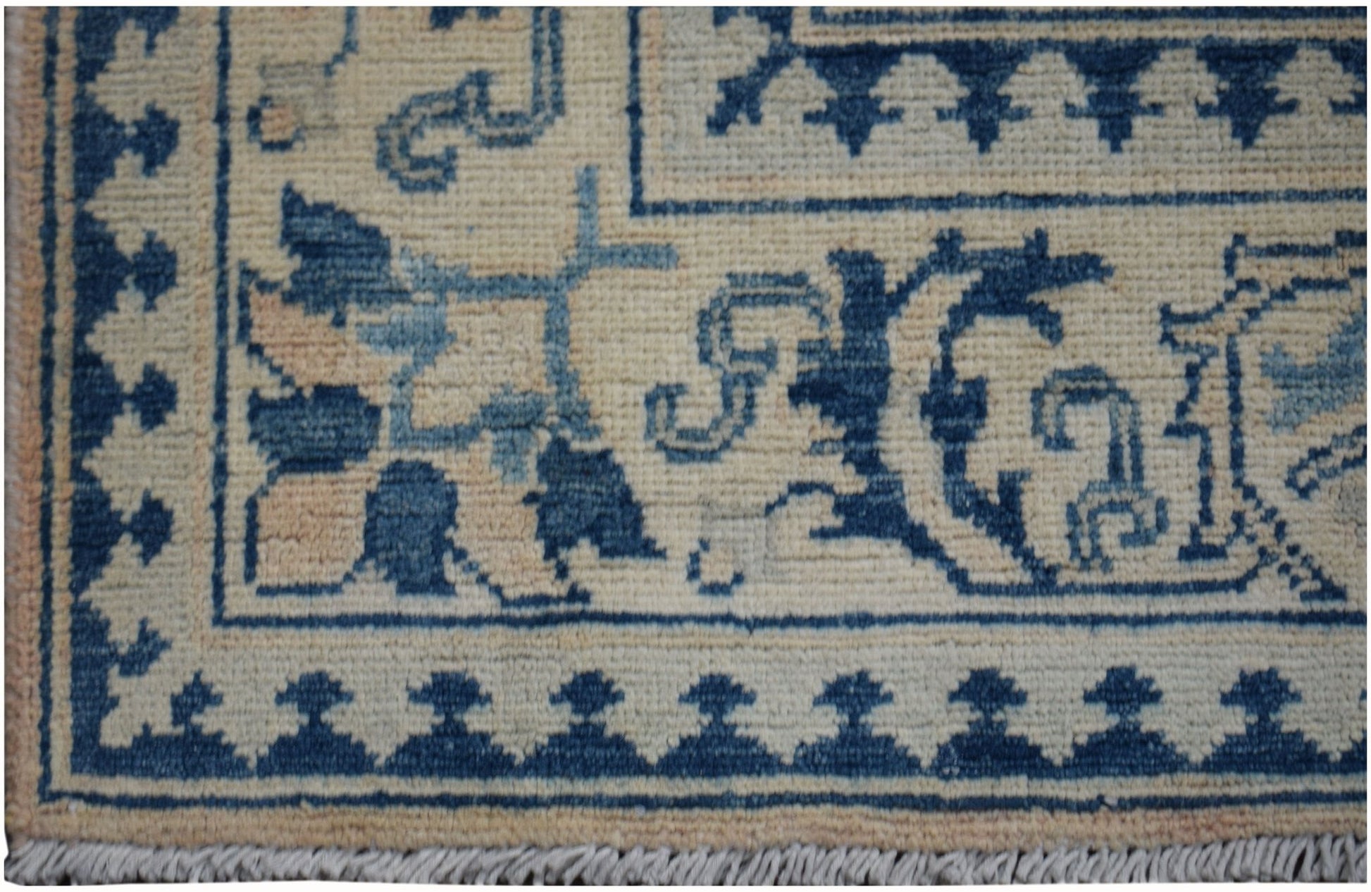 A handmade Afghan Kazakh runner featuring a beige background with blue geometric and floral patterns.