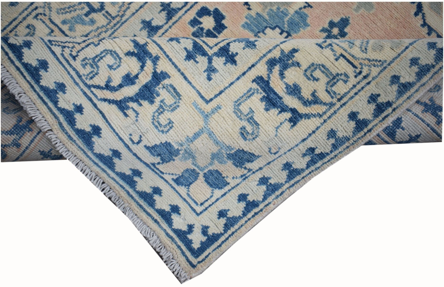 A handmade Afghan Kazakh runner featuring a blue and beige geometric pattern on a wool pile.