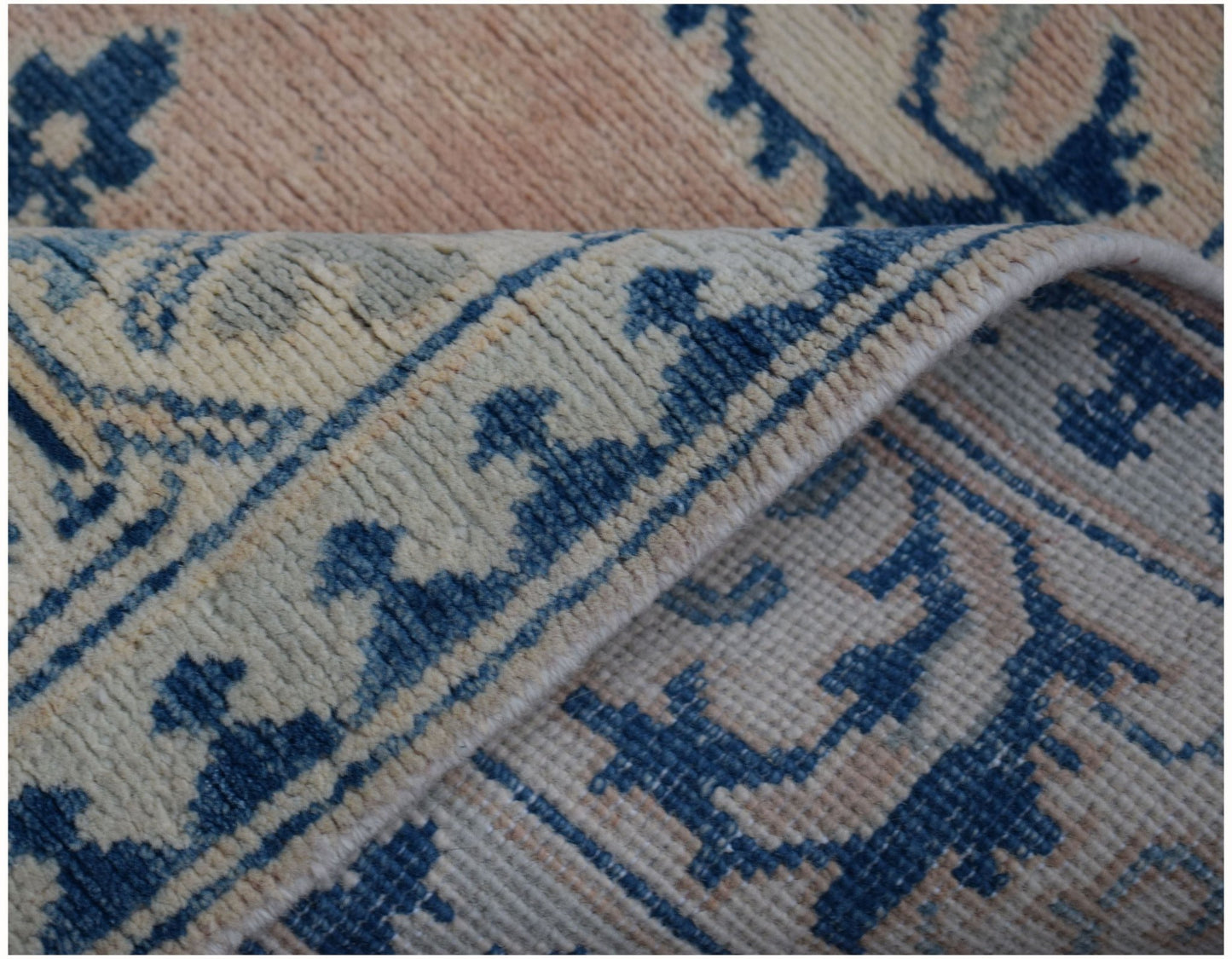 A close-up view of a handmade Afghan Kazakh runner featuring a blue and beige floral pattern.