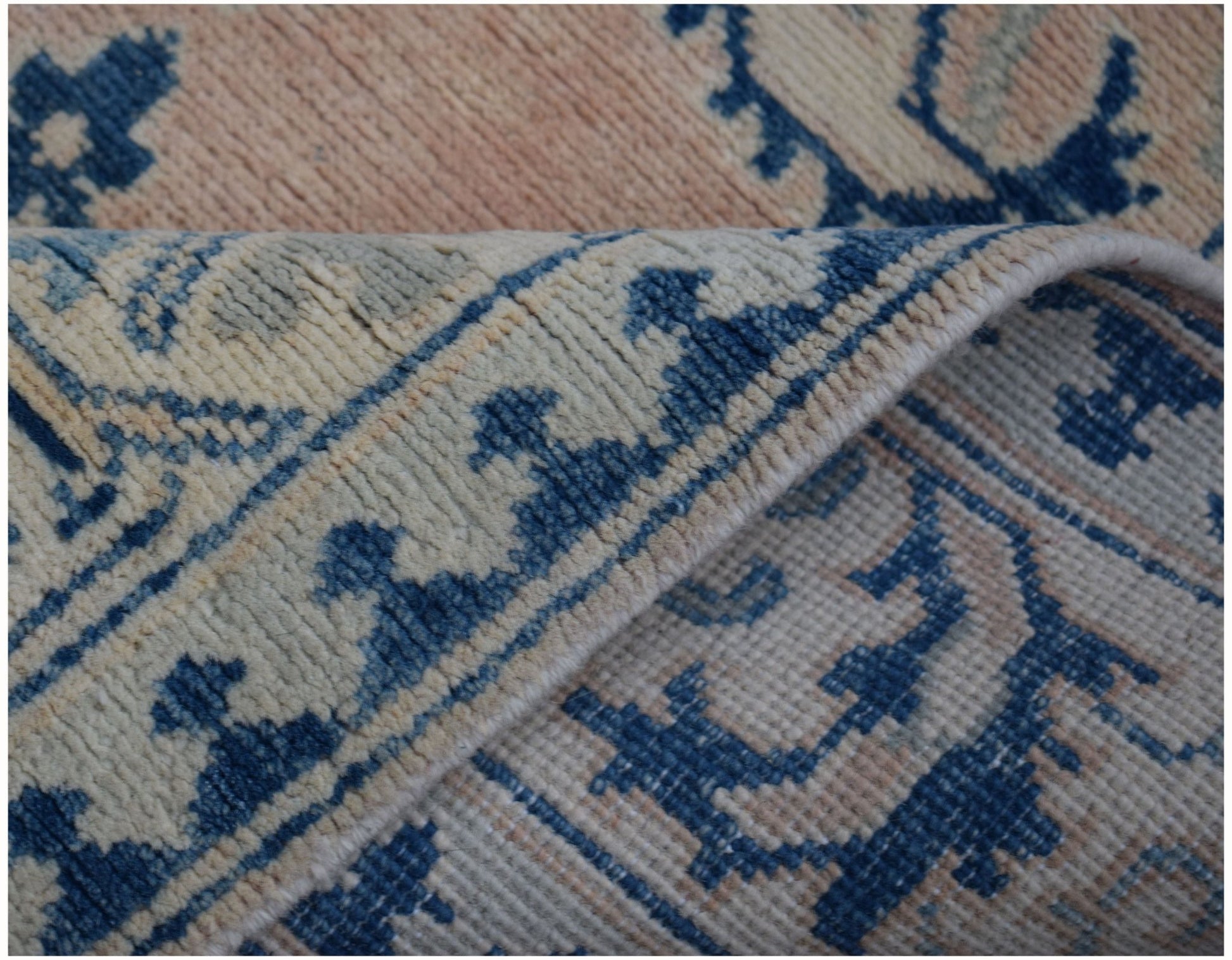 A close-up view of a handmade Afghan Kazakh runner featuring a blue and beige floral pattern.