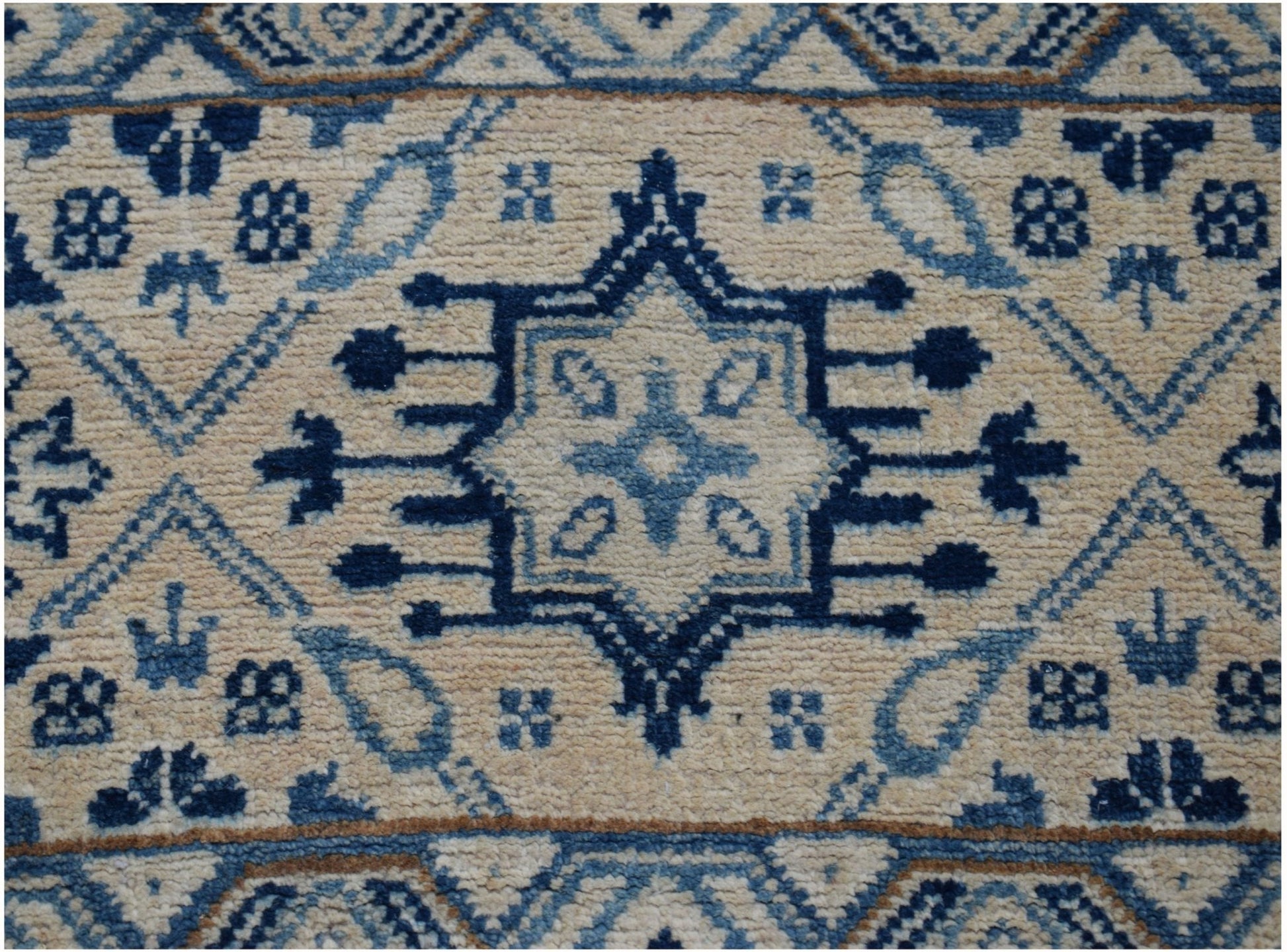 Handmade Afghan Kazakh runner rug featuring a central blue geometric medallion on a beige field.