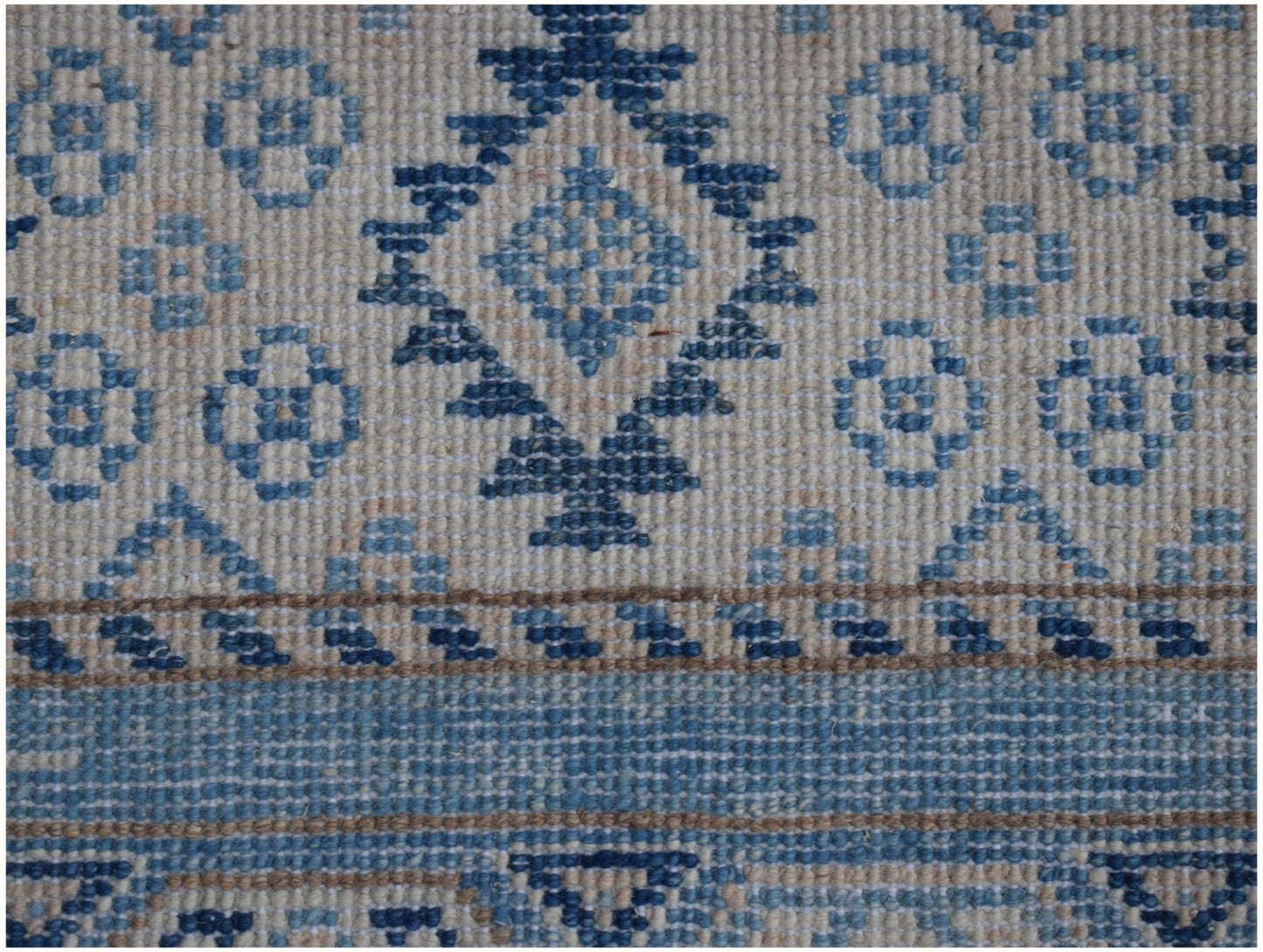 Handmade Afghan Kazakh runner featuring a geometric blue and beige pattern on a wool pile.