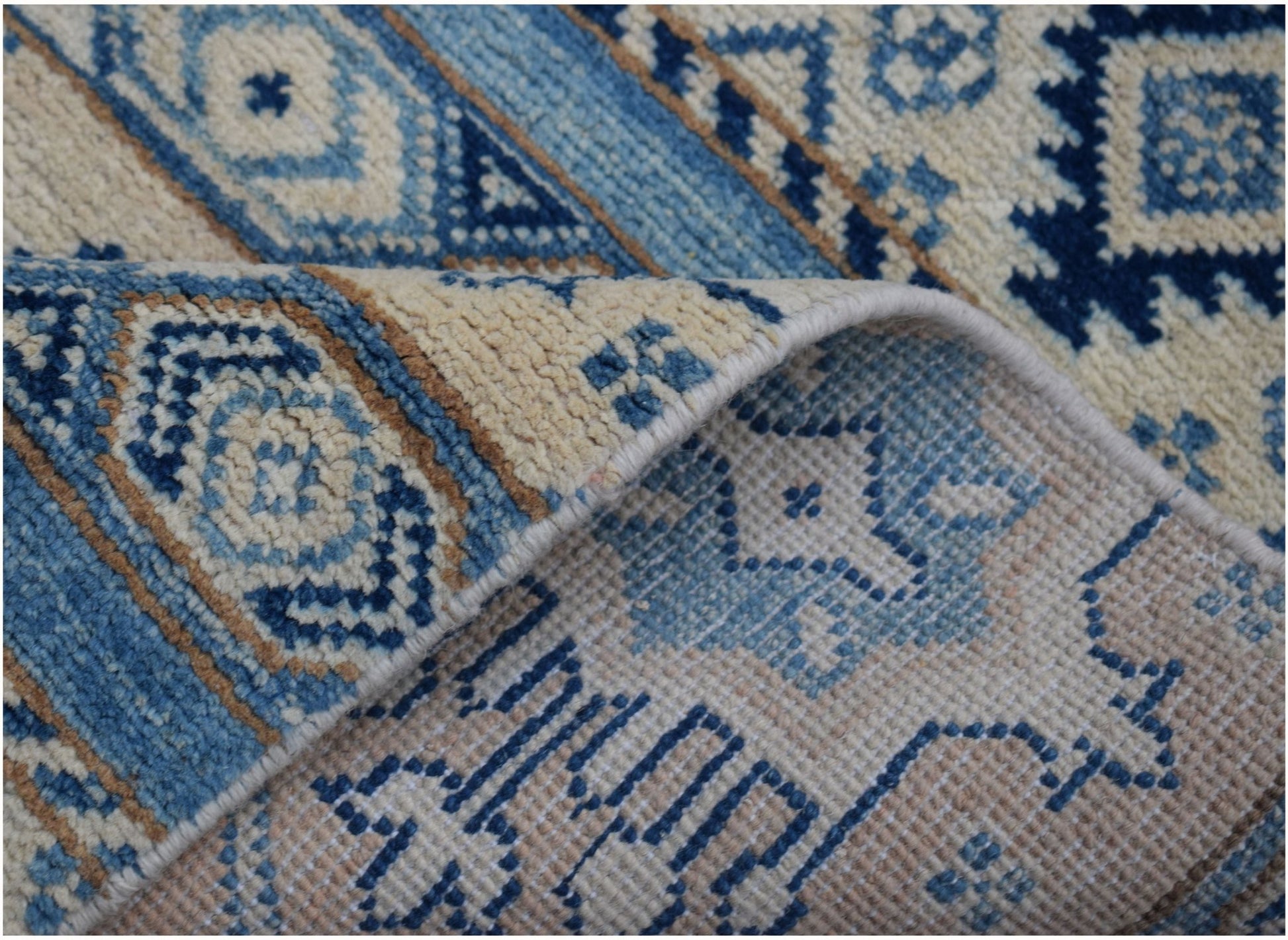 A handmade Afghan Kazakh runner rug featuring geometric patterns in shades of blue and beige.
