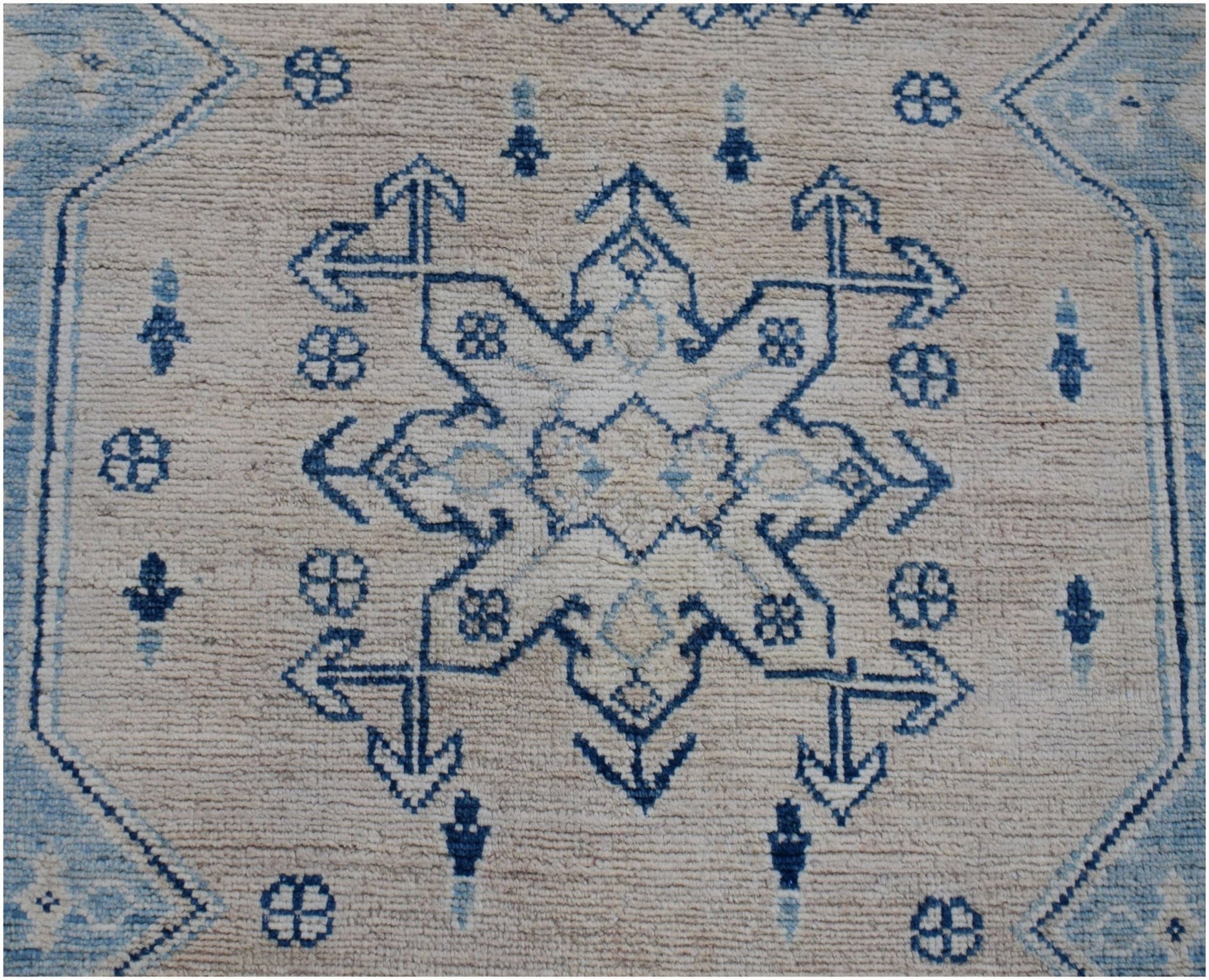 Handmade Afghan Kazakh runner rug featuring a blue geometric star pattern on a beige wool field.