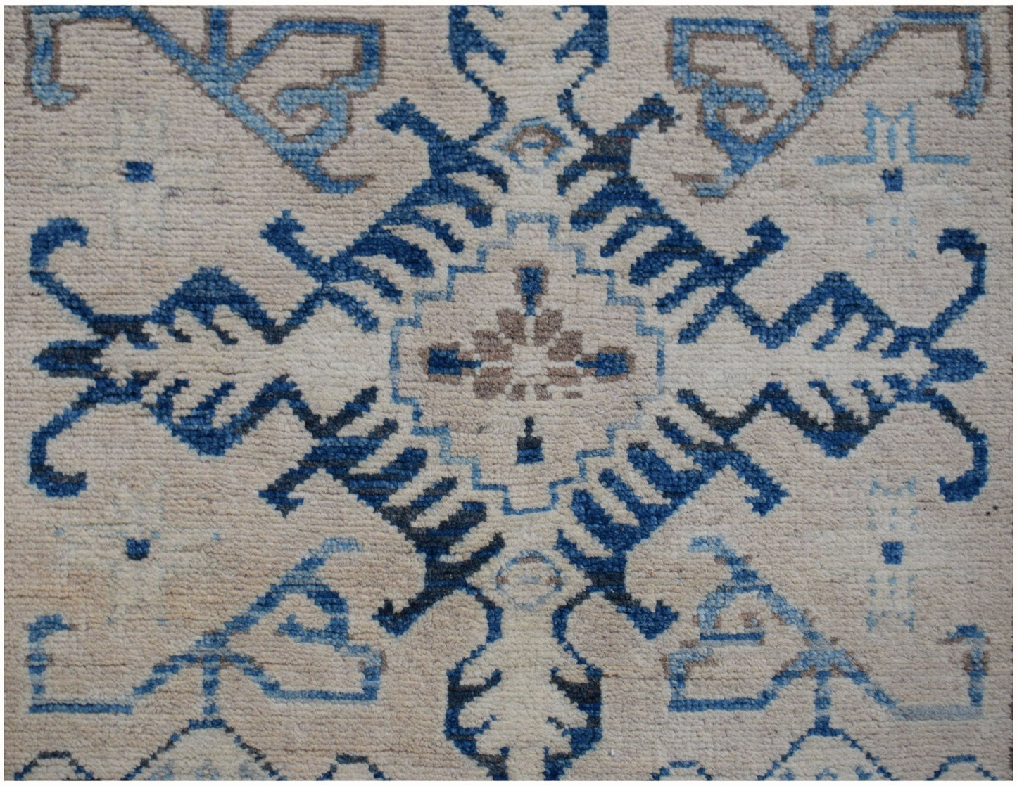 An Afghan Kazakh runner rug featuring a central blue and beige geometric medallion pattern.