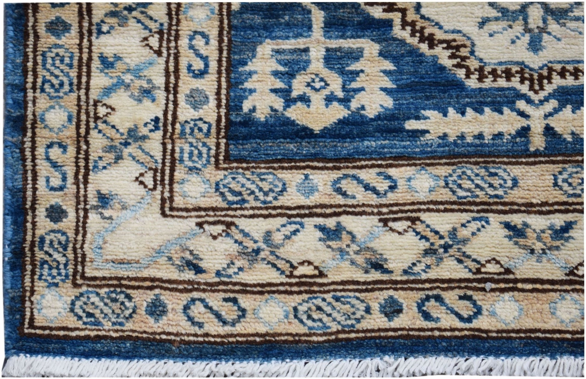 A handmade Afghan Kazakh runner featuring a geometric blue and beige pattern with a fringed edge.