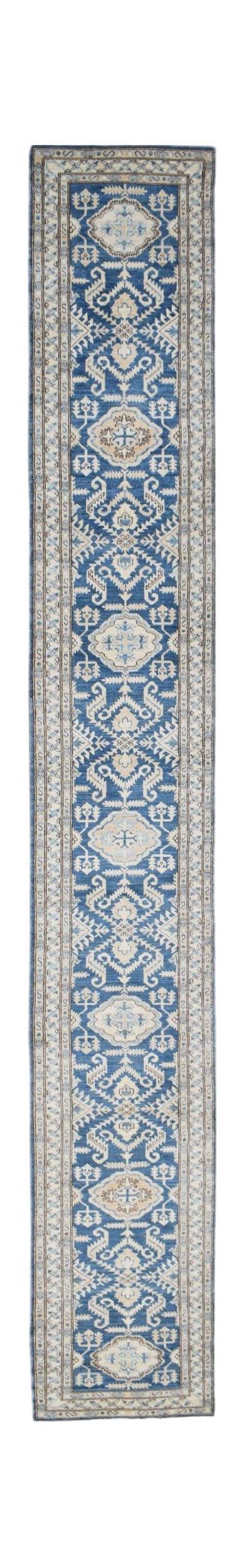 A long, handmade Afghan Kazakh runner rug featuring a repeating geometric pattern in blue and beige.