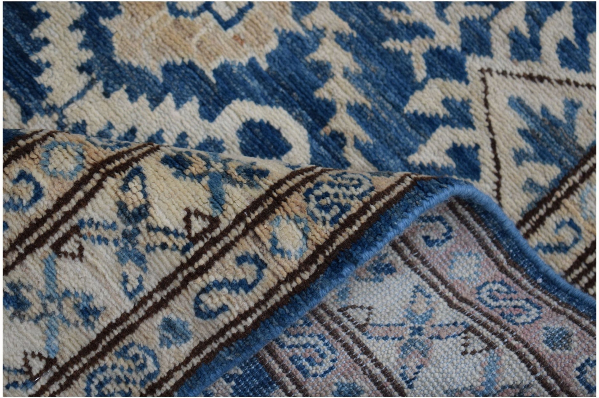 A handmade Afghan Kazakh runner featuring a traditional blue and beige geometric pattern.