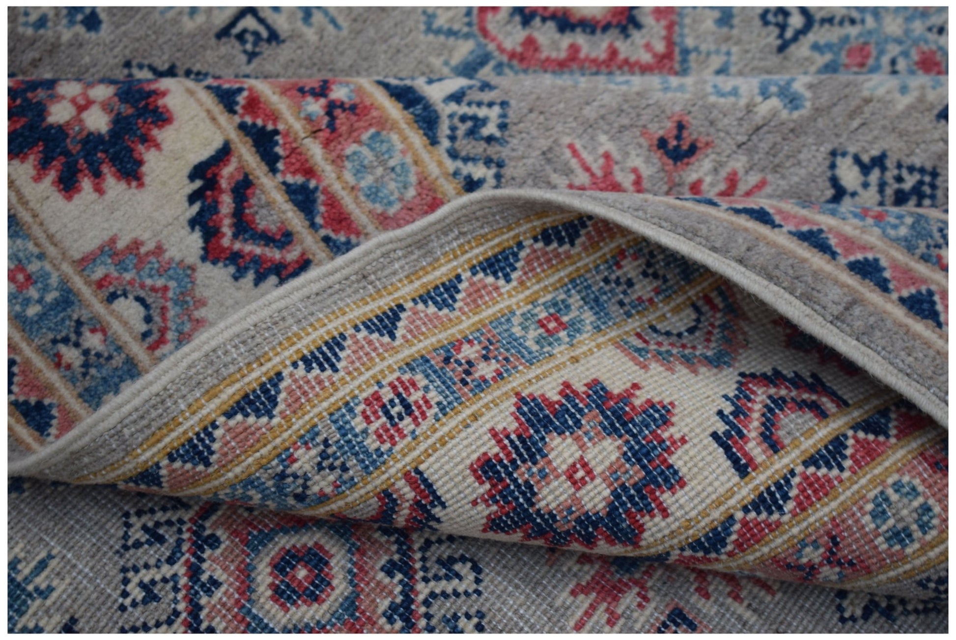 A handmade Afghan Kazakh rug featuring traditional geometric motifs in blue, red, and cream wool.