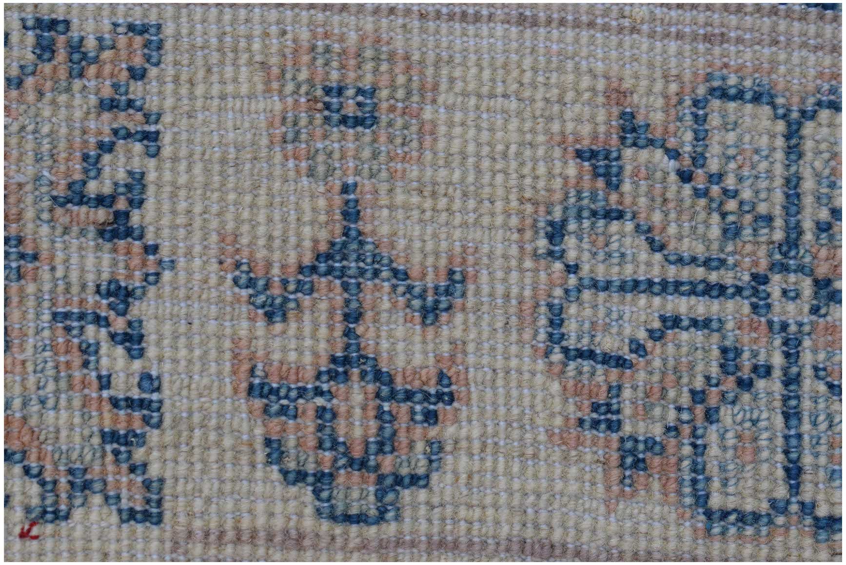 A close-up of an Afghan Kazakh rug featuring traditional blue and peach geometric floral patterns.