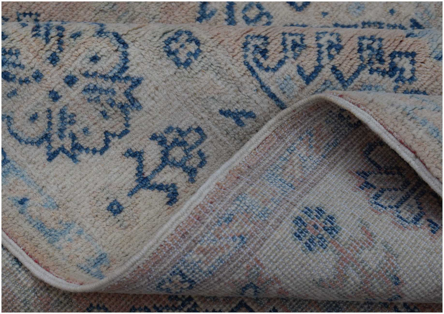 A handmade Afghan Kazakh rug featuring a traditional blue floral pattern on a beige wool base.