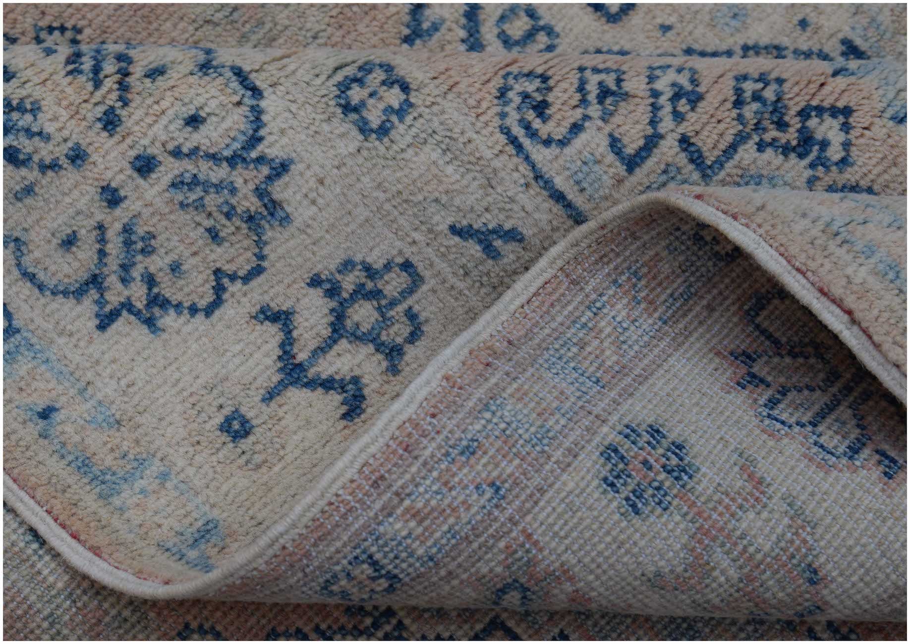A handmade Afghan Kazakh rug featuring a traditional blue floral pattern on a beige wool base.