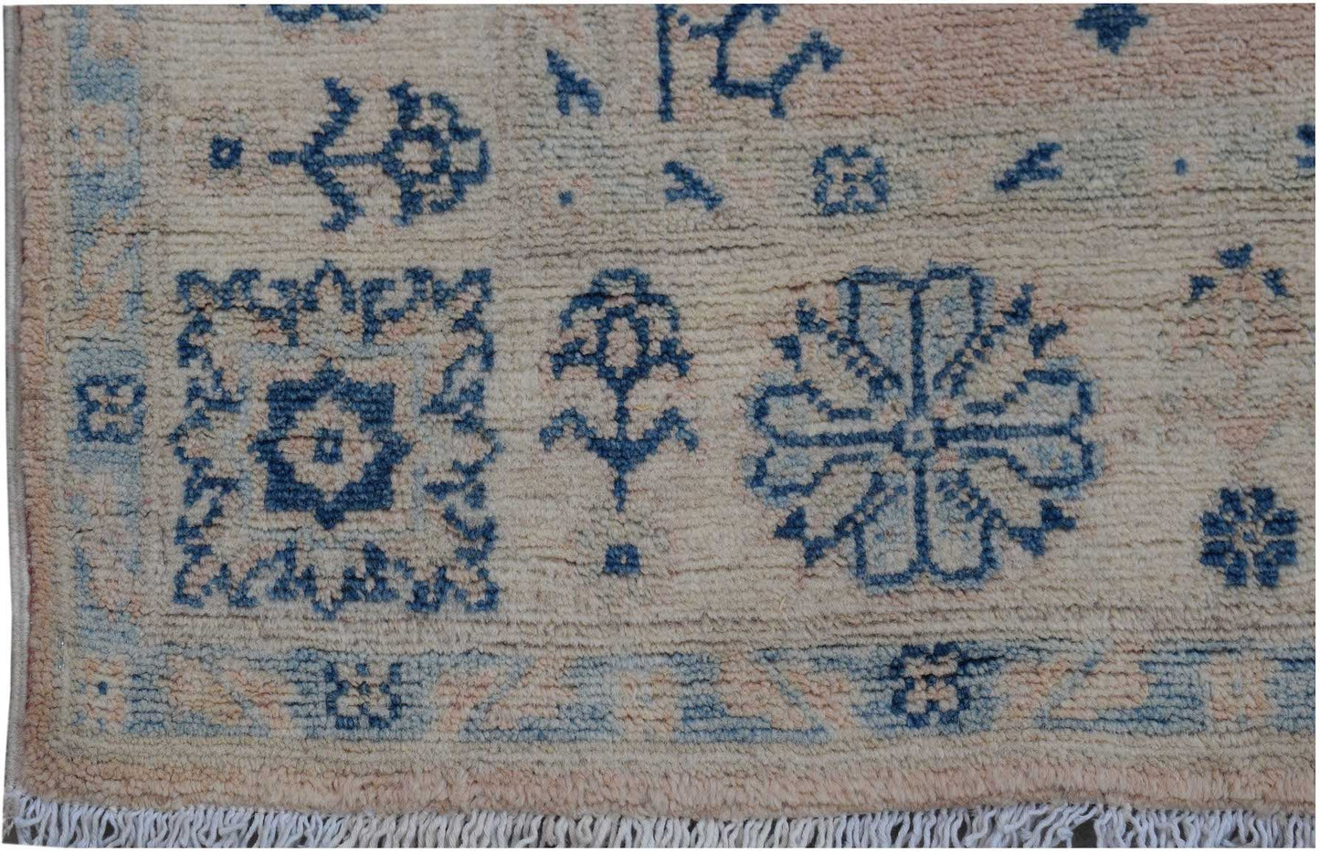 Handmade Afghan Kazakh rug featuring blue geometric and floral motifs on a beige wool background.