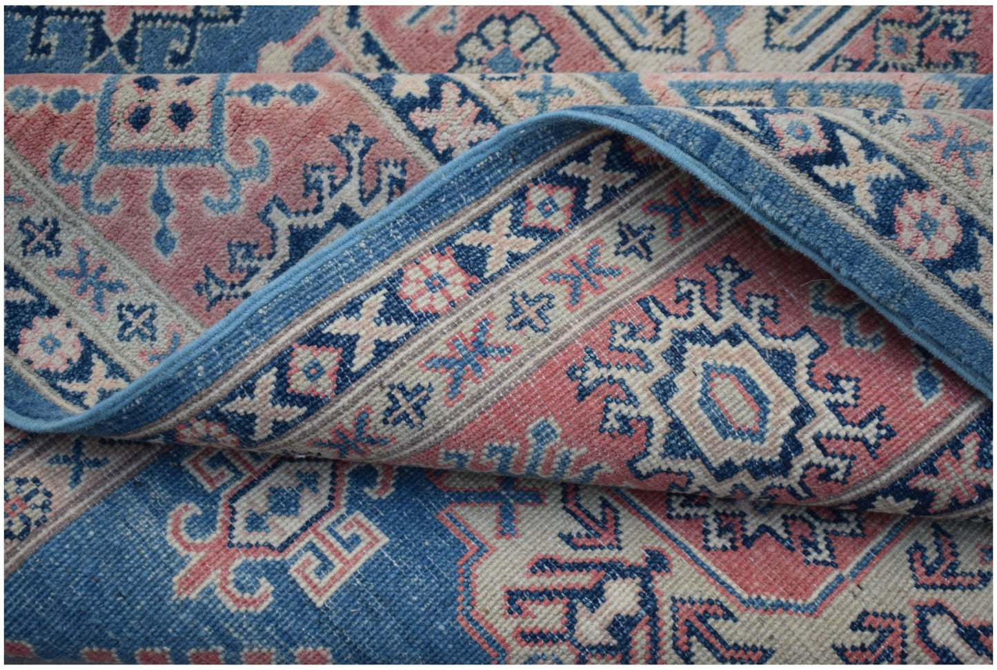 A handmade Afghan Kazakh rug featuring traditional geometric motifs in blue, pink, and cream.