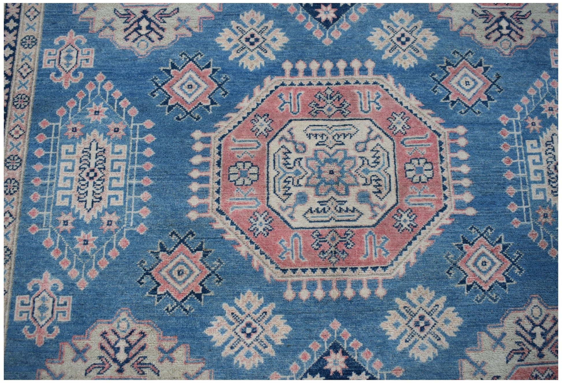 Handmade Afghan Kazakh rug featuring traditional geometric motifs in blue, pink, and cream wool.