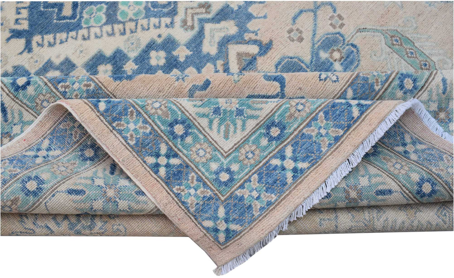 A handmade Afghan Kazakh rug featuring a beige field with intricate blue and grey floral patterns.