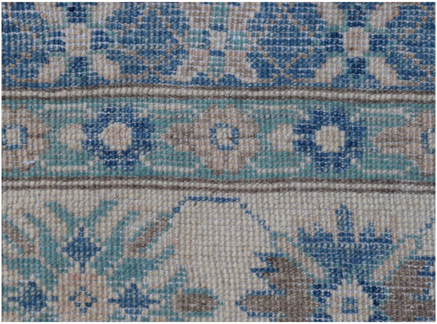 A close-up of an Afghan Kazakh rug featuring intricate floral patterns in blue, beige, and grey.