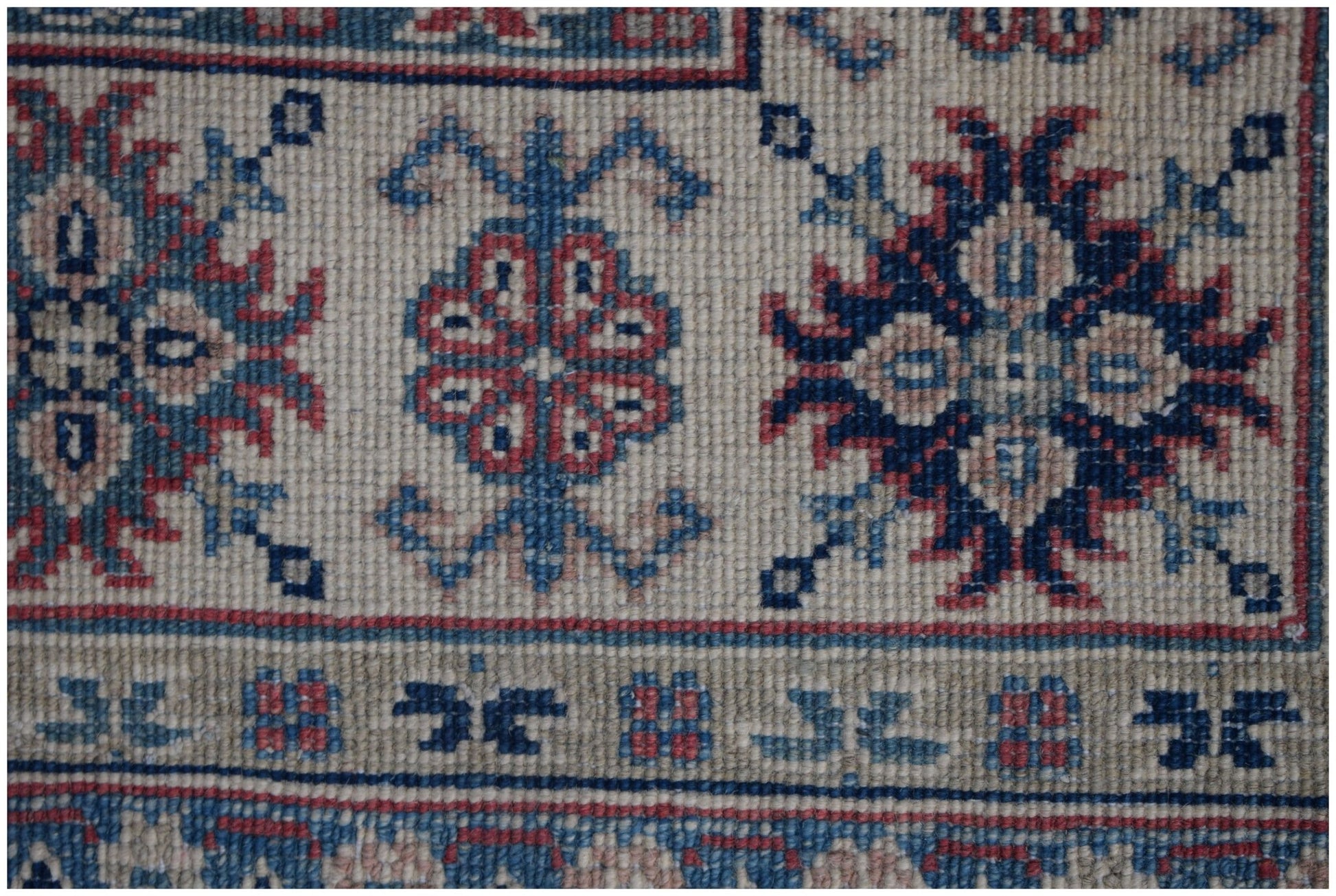 A handmade Afghan Kazakh rug featuring traditional geometric motifs in blue, red, and cream wool.