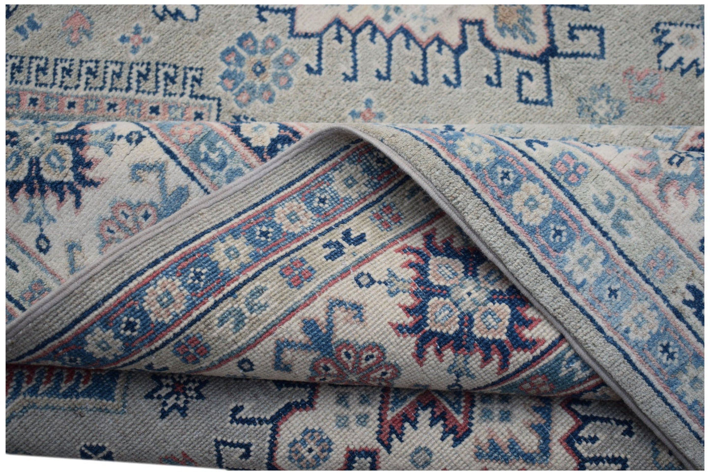 Handmade Afghan Kazakh rug featuring traditional blue and pink geometric motifs on a cream base.