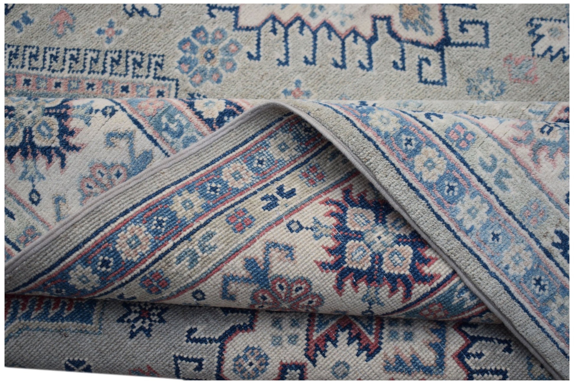 Handmade Afghan Kazakh rug featuring traditional blue and pink geometric motifs on a cream base.
