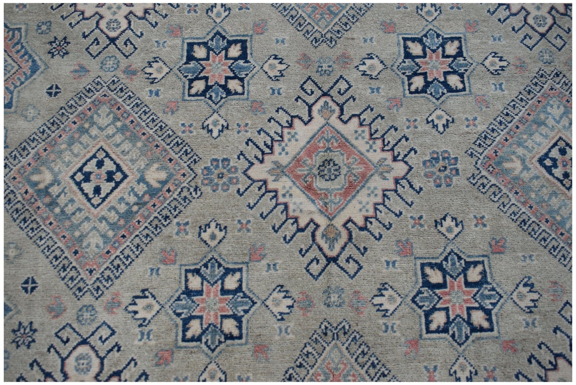 Handmade Afghan Kazakh rug featuring traditional geometric motifs in blue, pink, and cream tones.