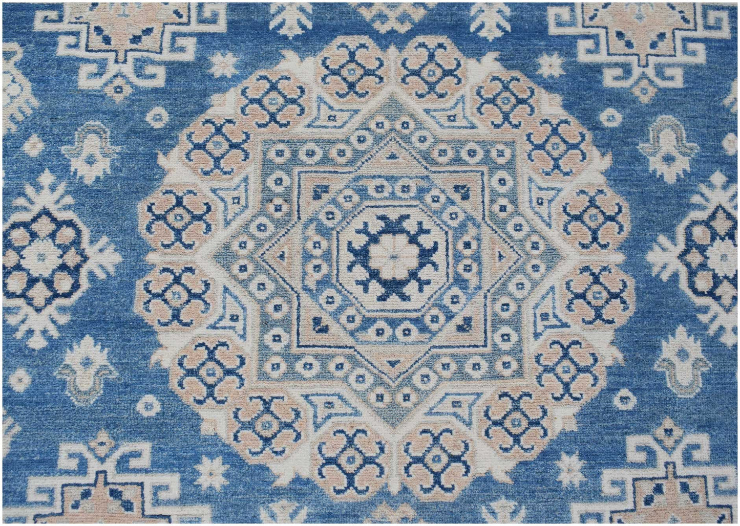 Handmade Afghan Kazakh rug featuring a central geometric medallion in blue, beige, and grey.