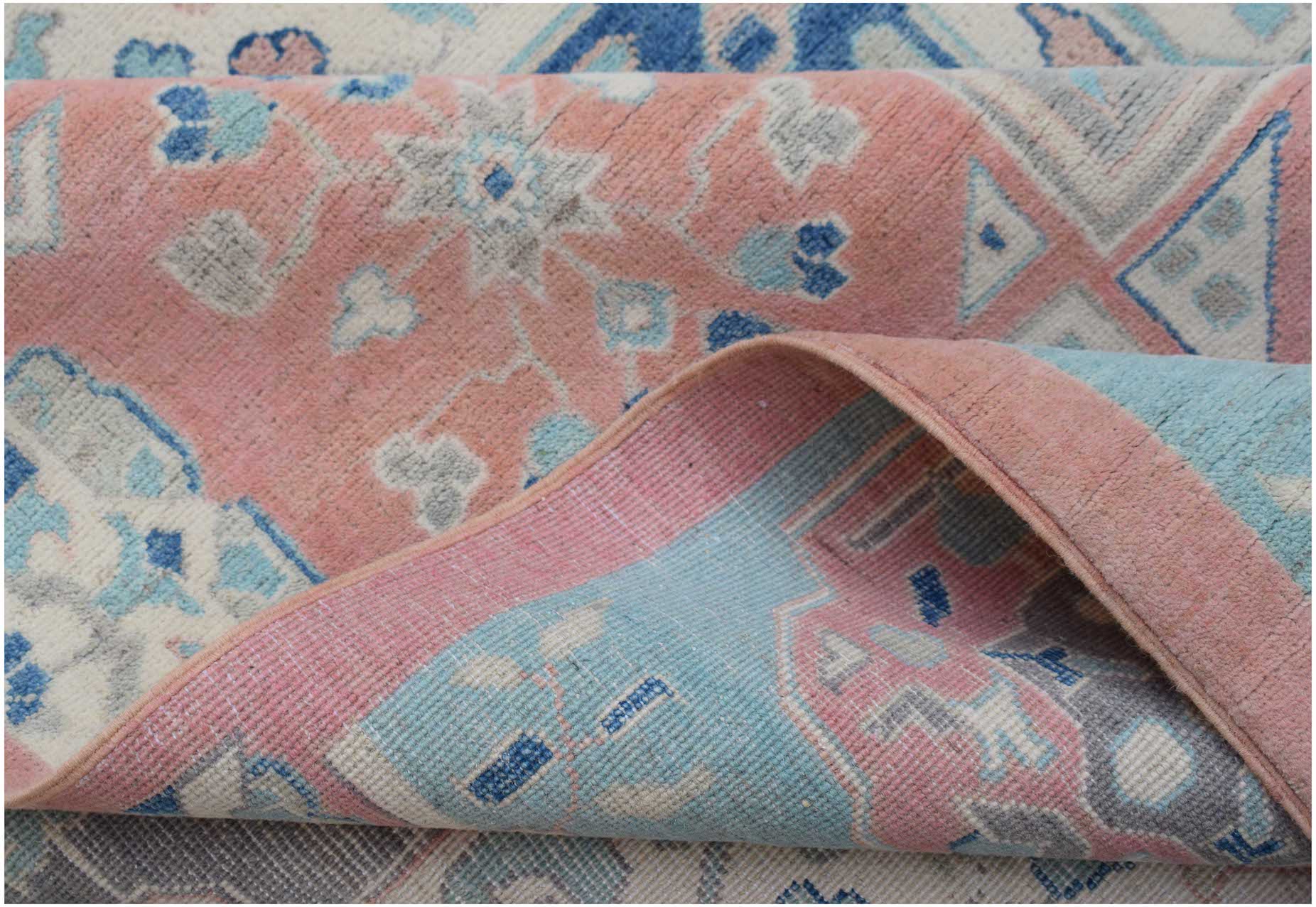 A handmade Afghan Kazakh rug featuring traditional geometric motifs in soft pink and blue tones.