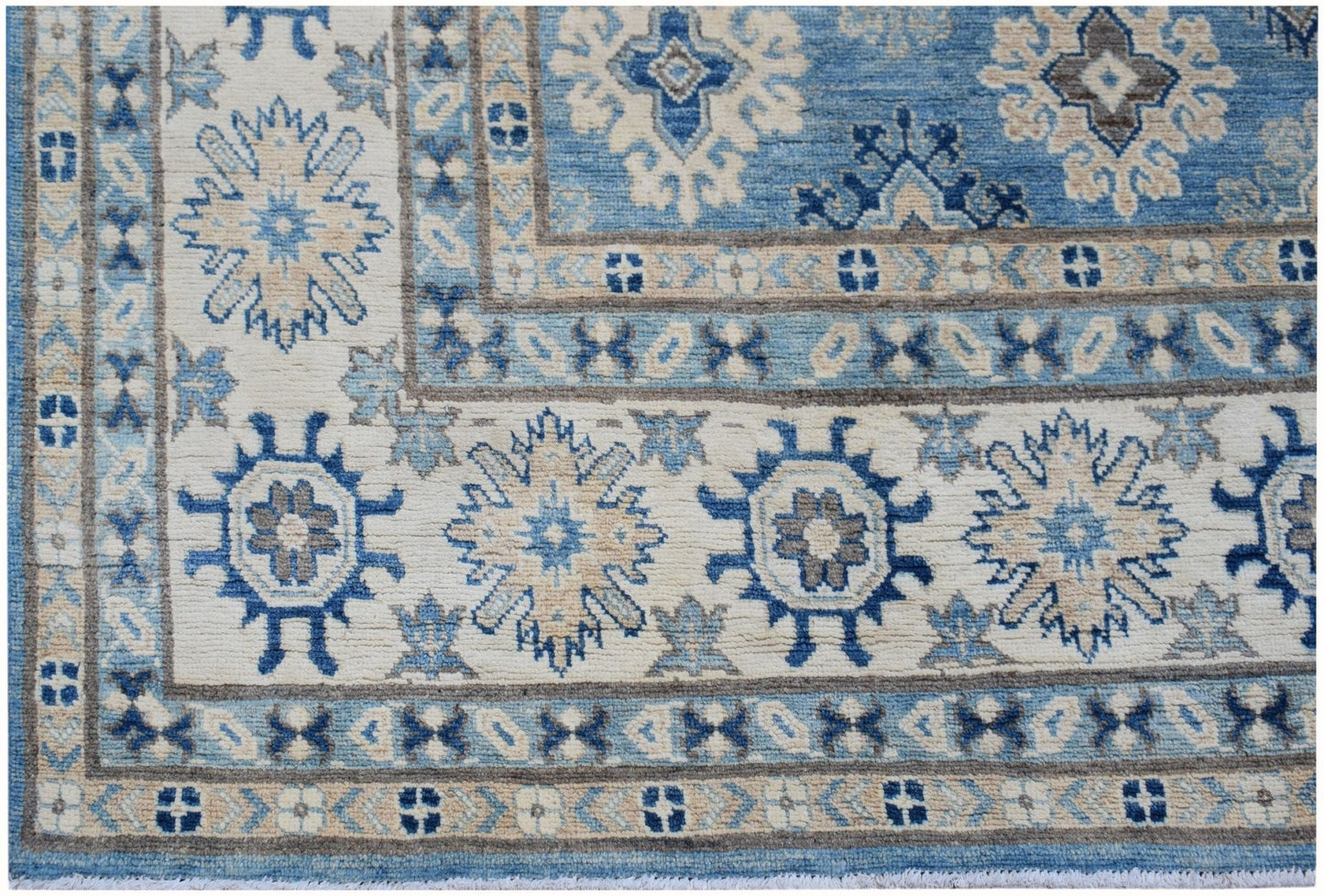An Afghan Kazakh rug featuring a geometric floral pattern in shades of blue, beige, and grey.