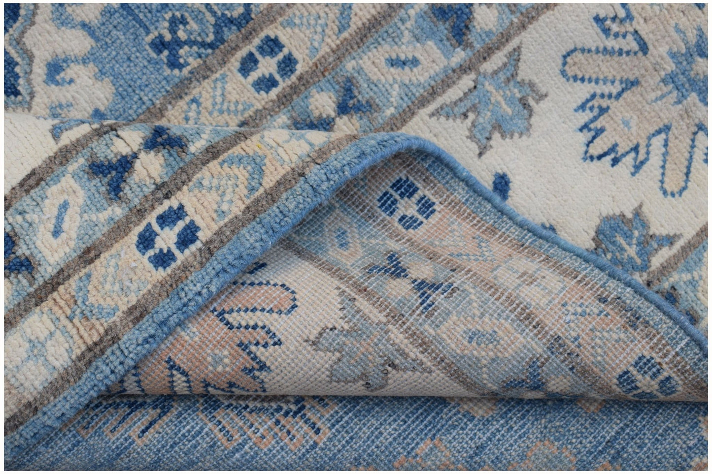 A handmade Afghan Kazakh rug featuring a blue, beige, and grey geometric pattern.