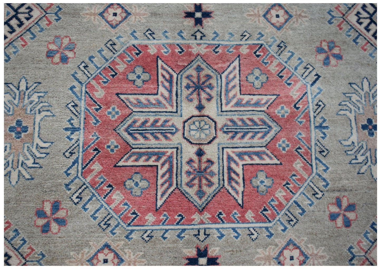Handmade Afghan Kazakh rug featuring a central geometric star motif in red, blue, and cream.
