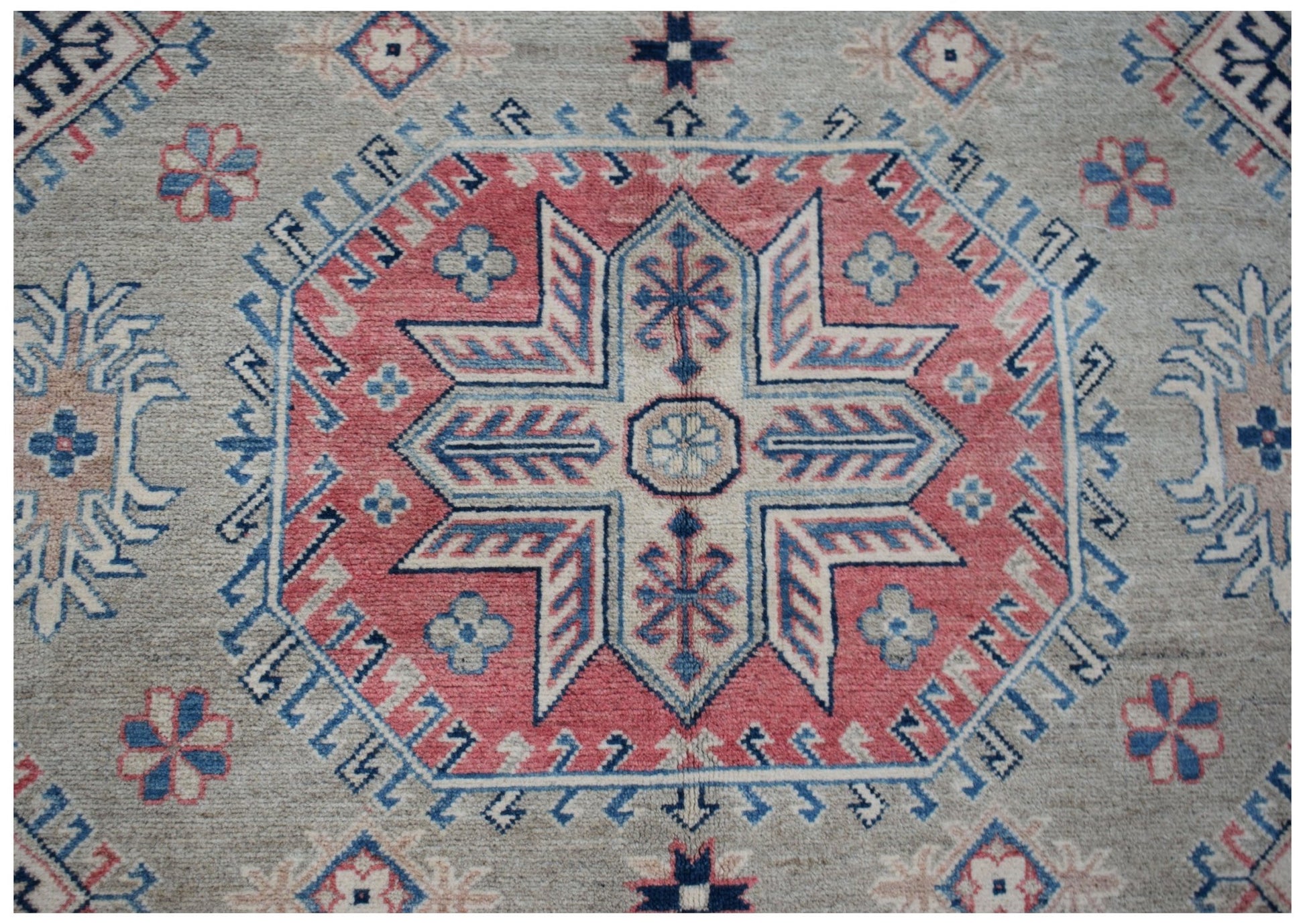 Handmade Afghan Kazakh rug featuring a central geometric star motif in red, blue, and cream.