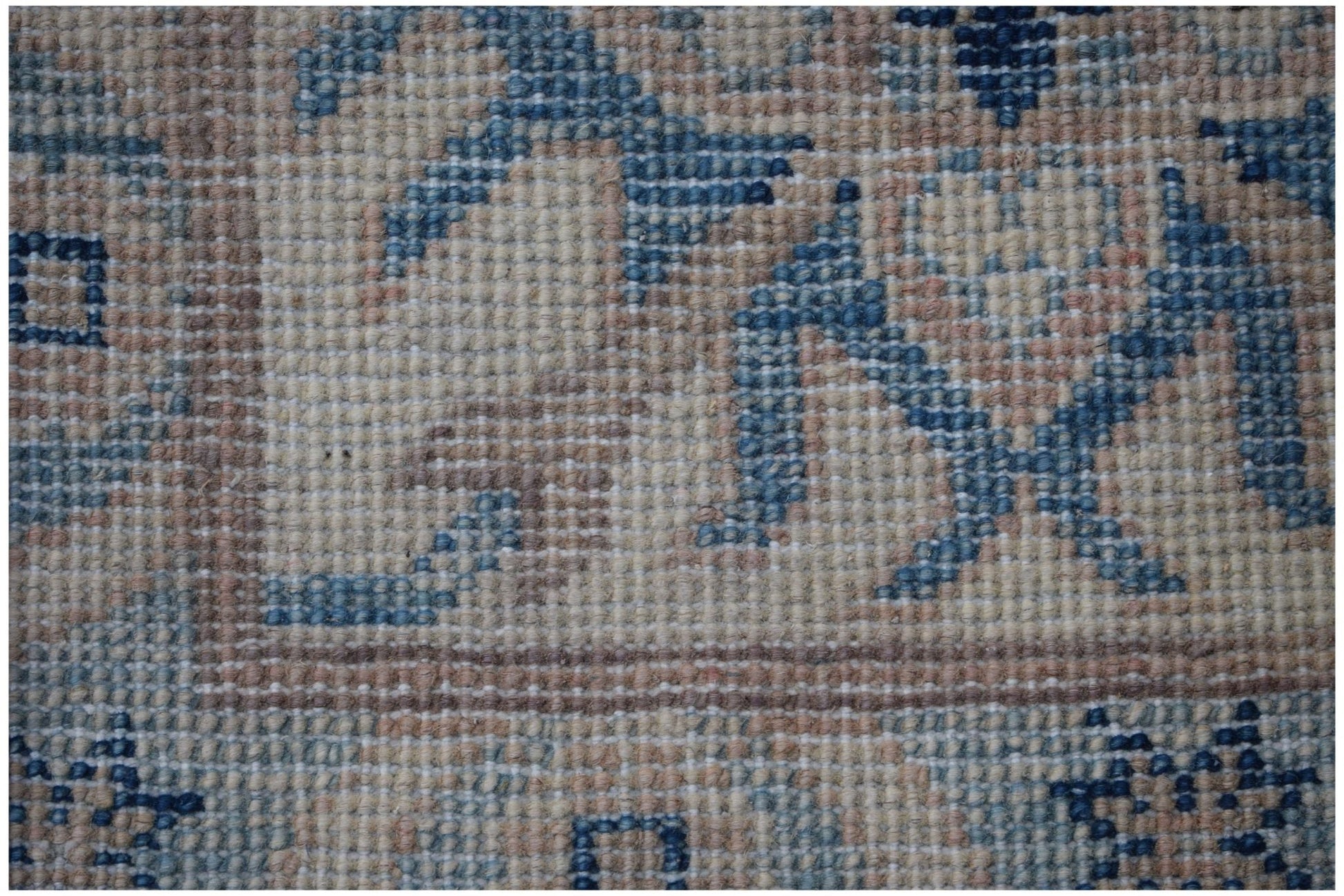 A close-up view of a handmade Afghan Kazakh rug featuring traditional geometric patterns in blue.