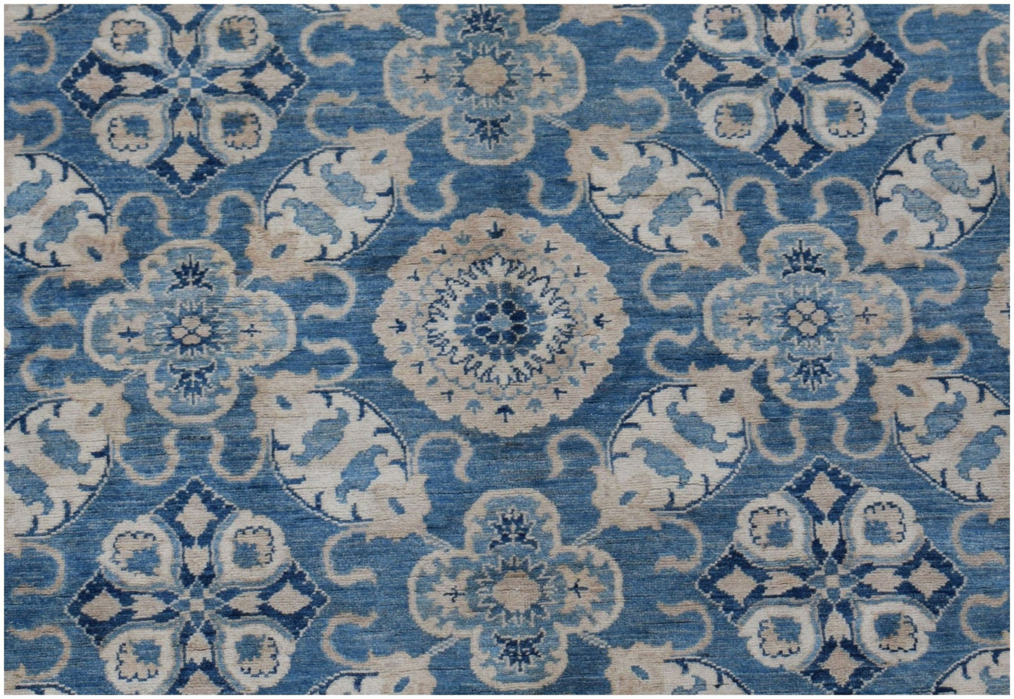 An Afghan Kazakh rug featuring a repeating blue and cream floral medallion pattern.