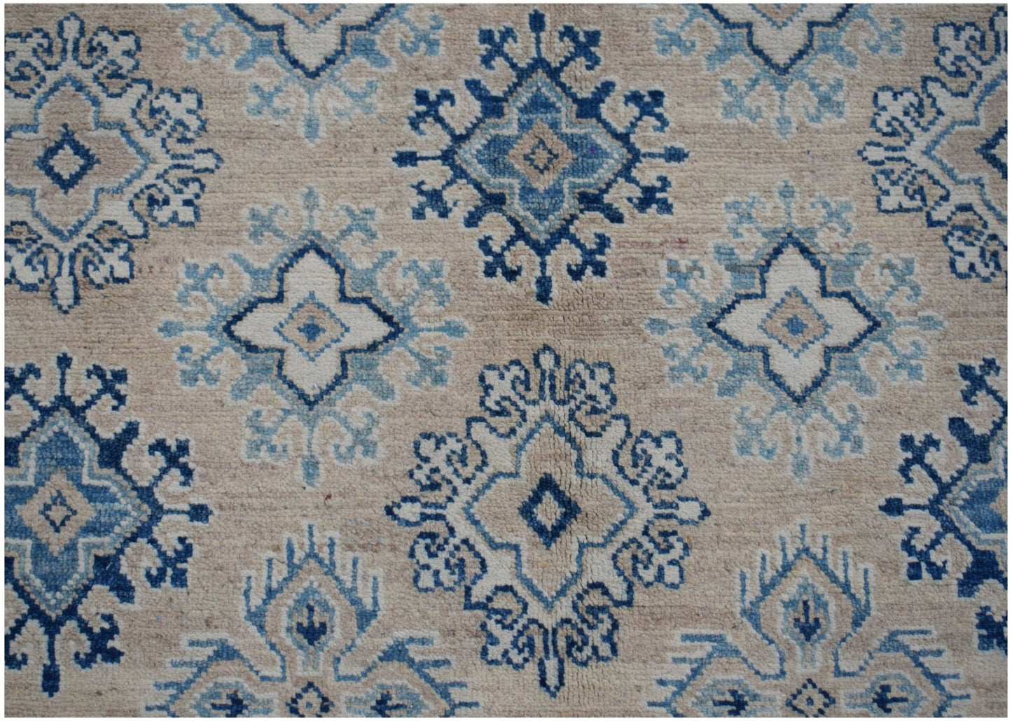 Handmade Afghan Kazakh rug featuring a repeating geometric floral pattern in blue and beige tones.