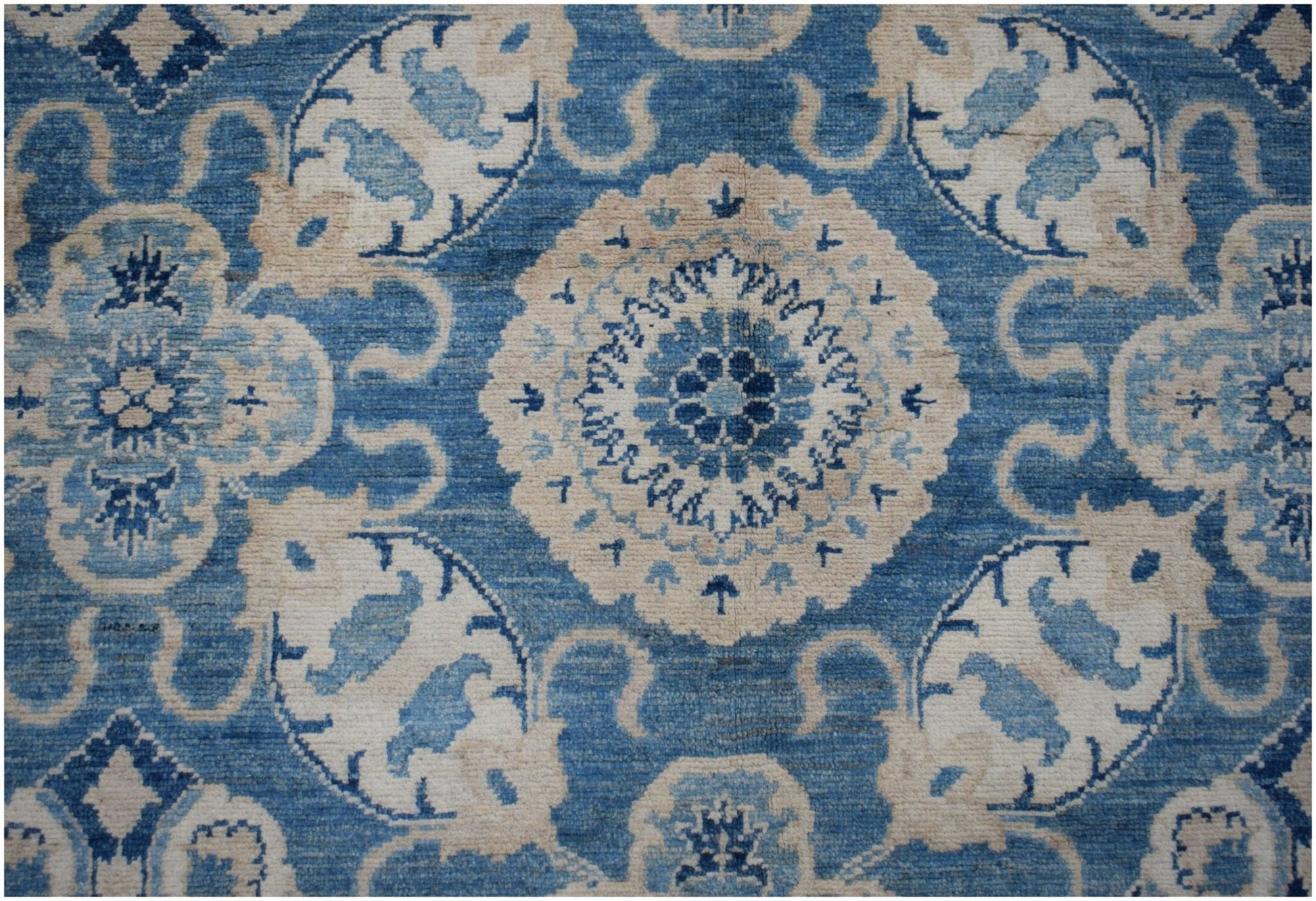 Handmade Afghan Kazakh rug featuring a traditional blue and cream floral medallion pattern.