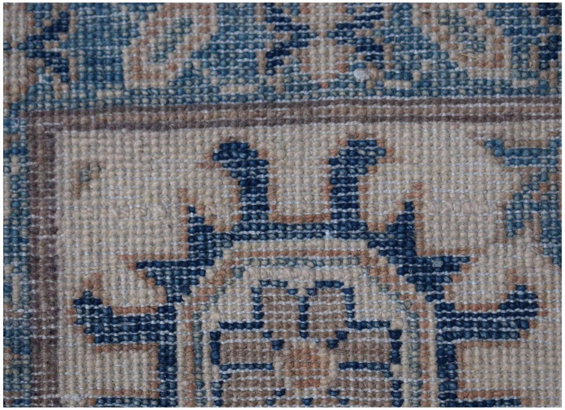 A close-up of a handmade Afghan Kazakh rug featuring traditional blue and beige geometric patterns.