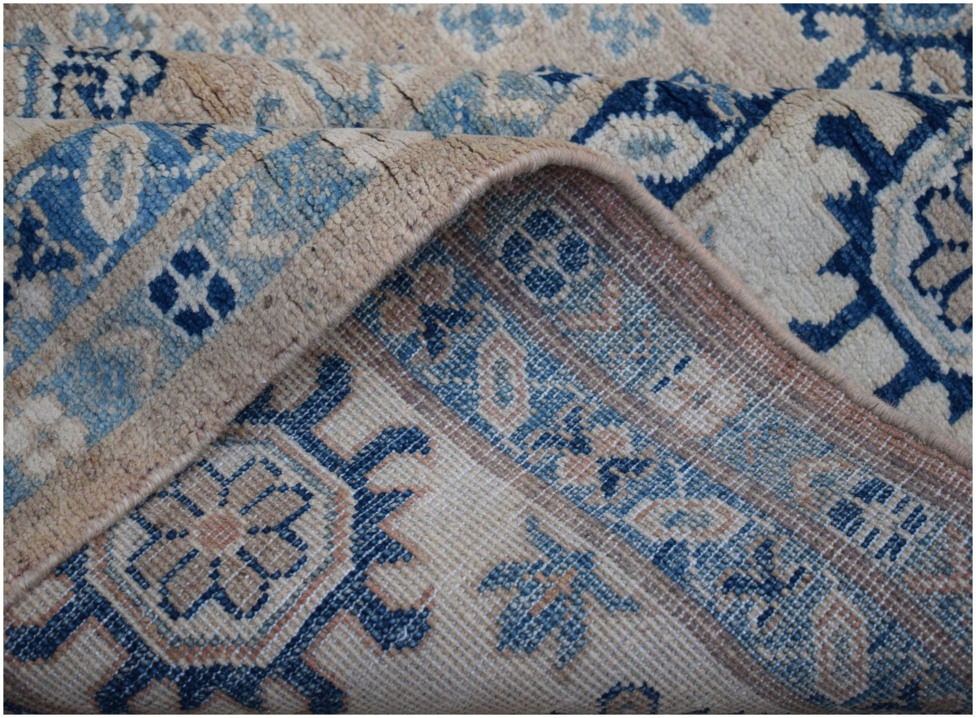 A handmade Afghan Kazakh wool rug featuring traditional blue and beige geometric patterns.