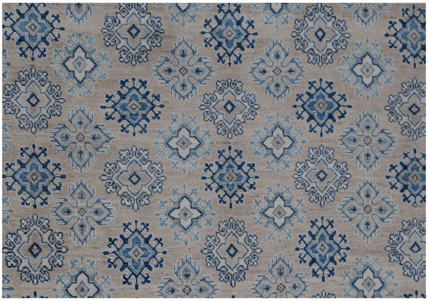 Handmade Afghan Kazakh rug featuring a repeating geometric floral pattern in blue and beige tones.