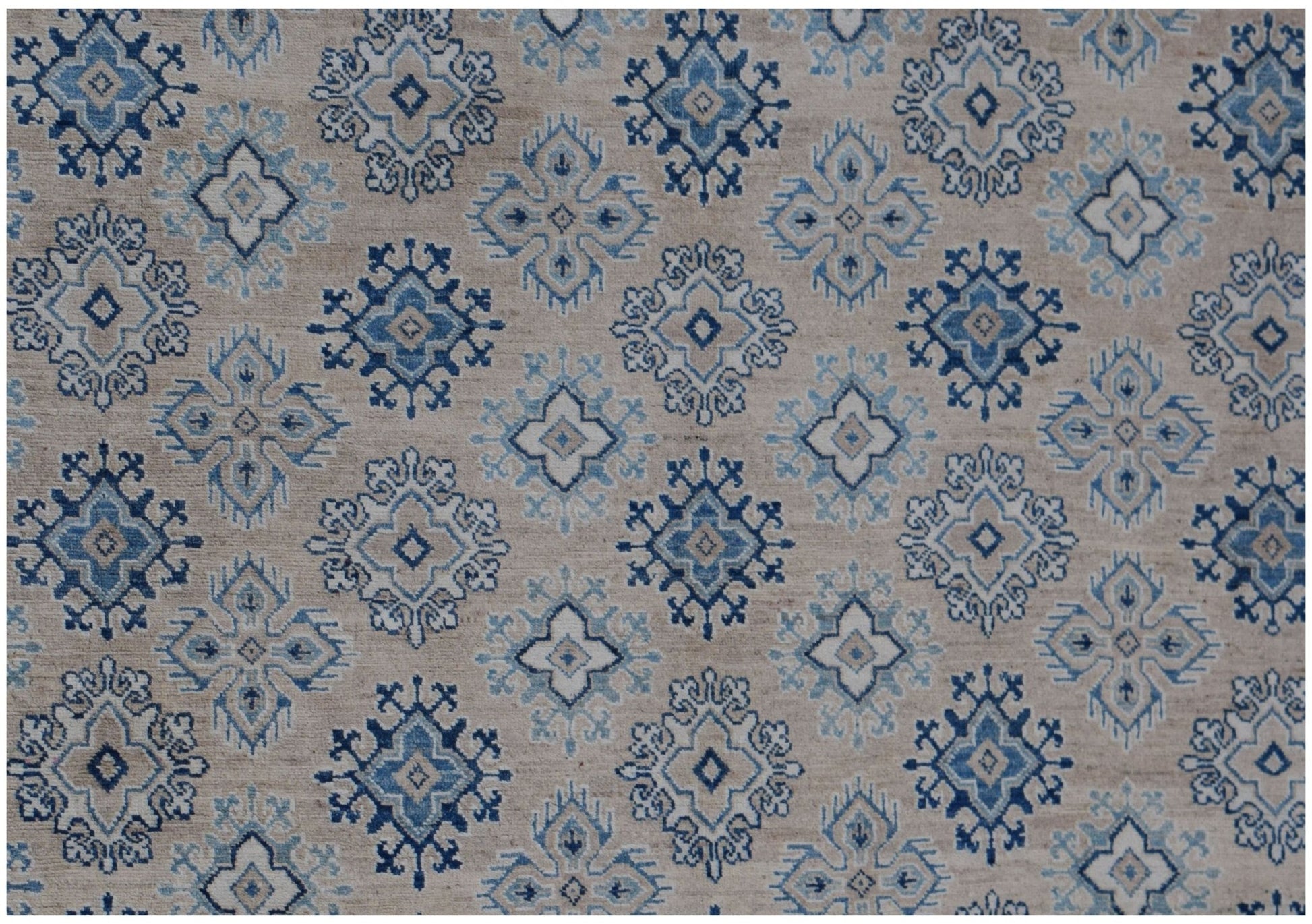Handmade Afghan Kazakh rug featuring a repeating geometric floral pattern in blue and beige tones.