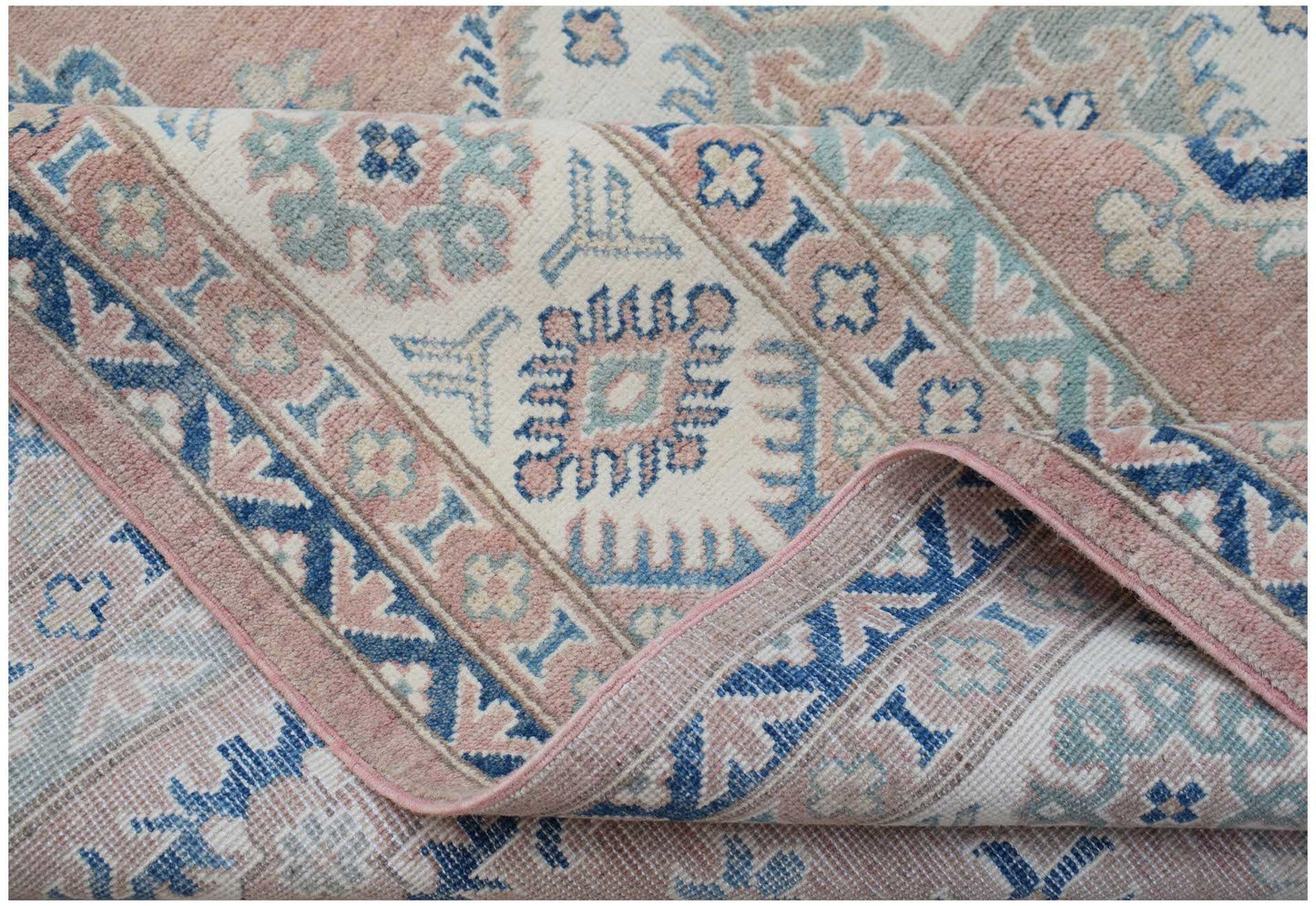 A handmade Afghan Kazakh rug featuring traditional geometric motifs in shades of pink and blue.