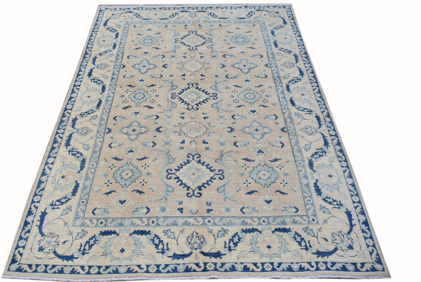 A handmade Afghan Kazakh rug featuring traditional blue geometric patterns on a beige wool field.