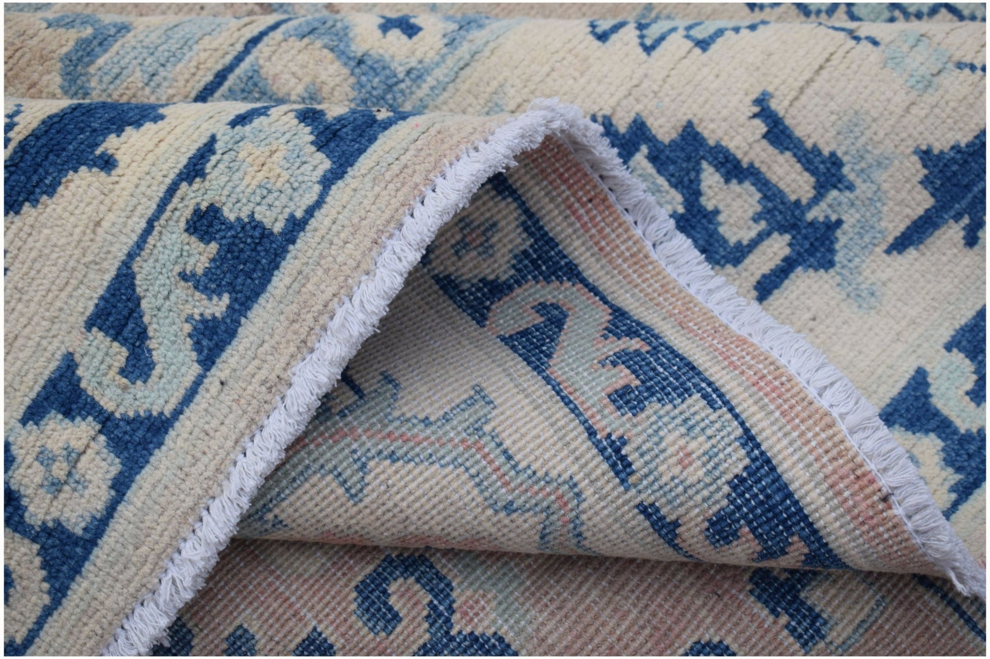 A handmade Afghan Kazakh rug featuring a traditional blue and cream geometric pattern.
