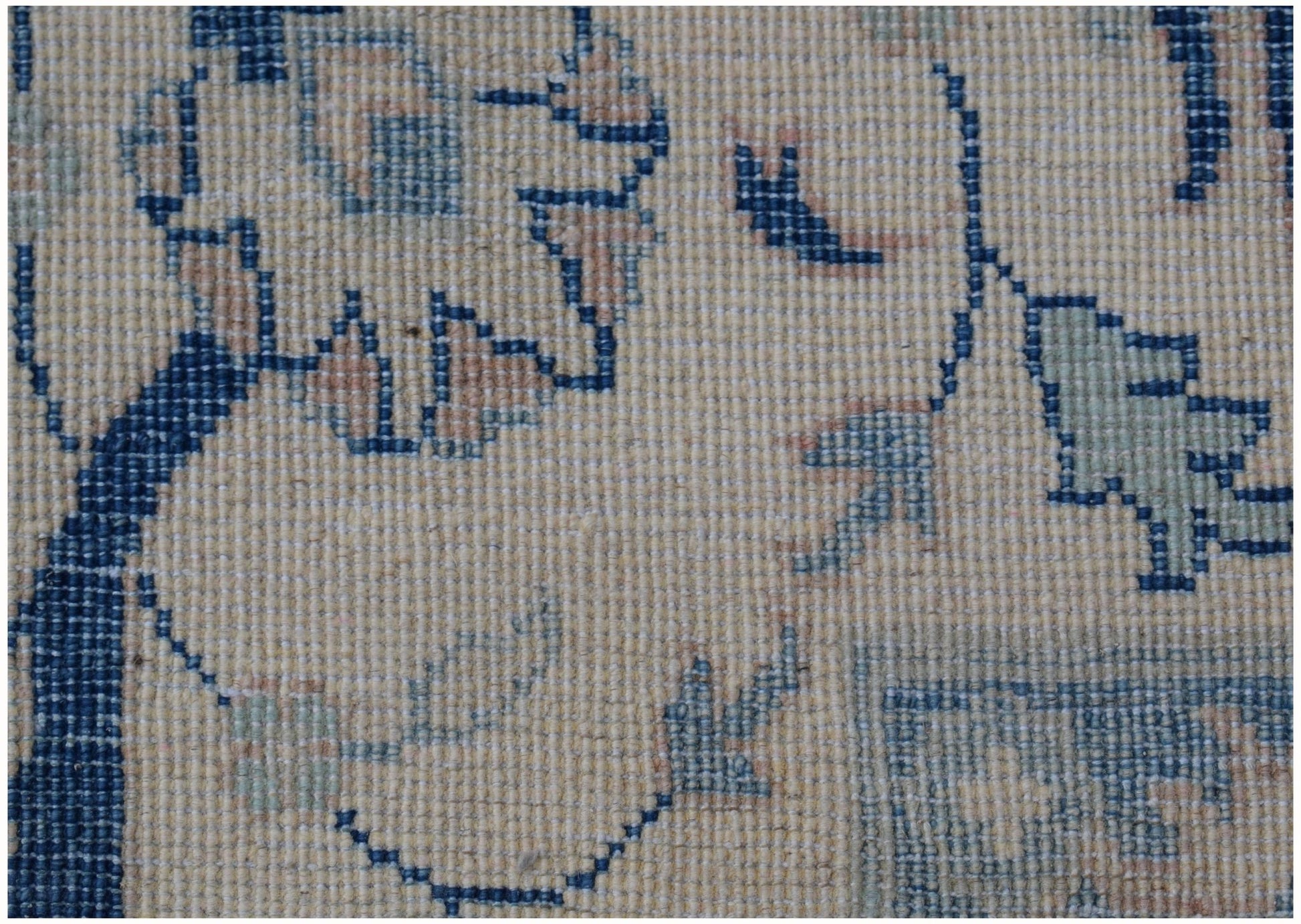 A close-up of a handmade Afghan Kazakh rug featuring traditional floral patterns in blue and beige.