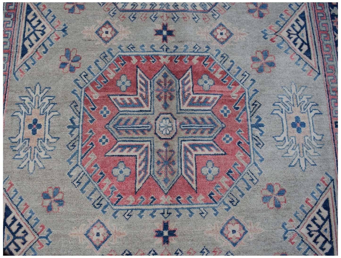 Handmade Afghan Kazakh rug featuring a central geometric medallion in red, blue, and cream wool.