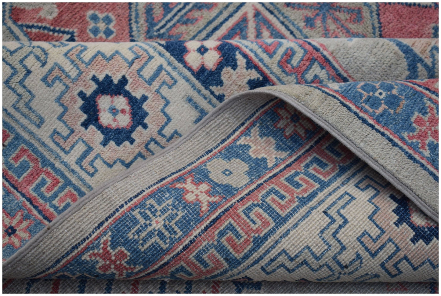 A handmade Afghan Kazakh rug featuring traditional geometric motifs in blue, pink, and cream.