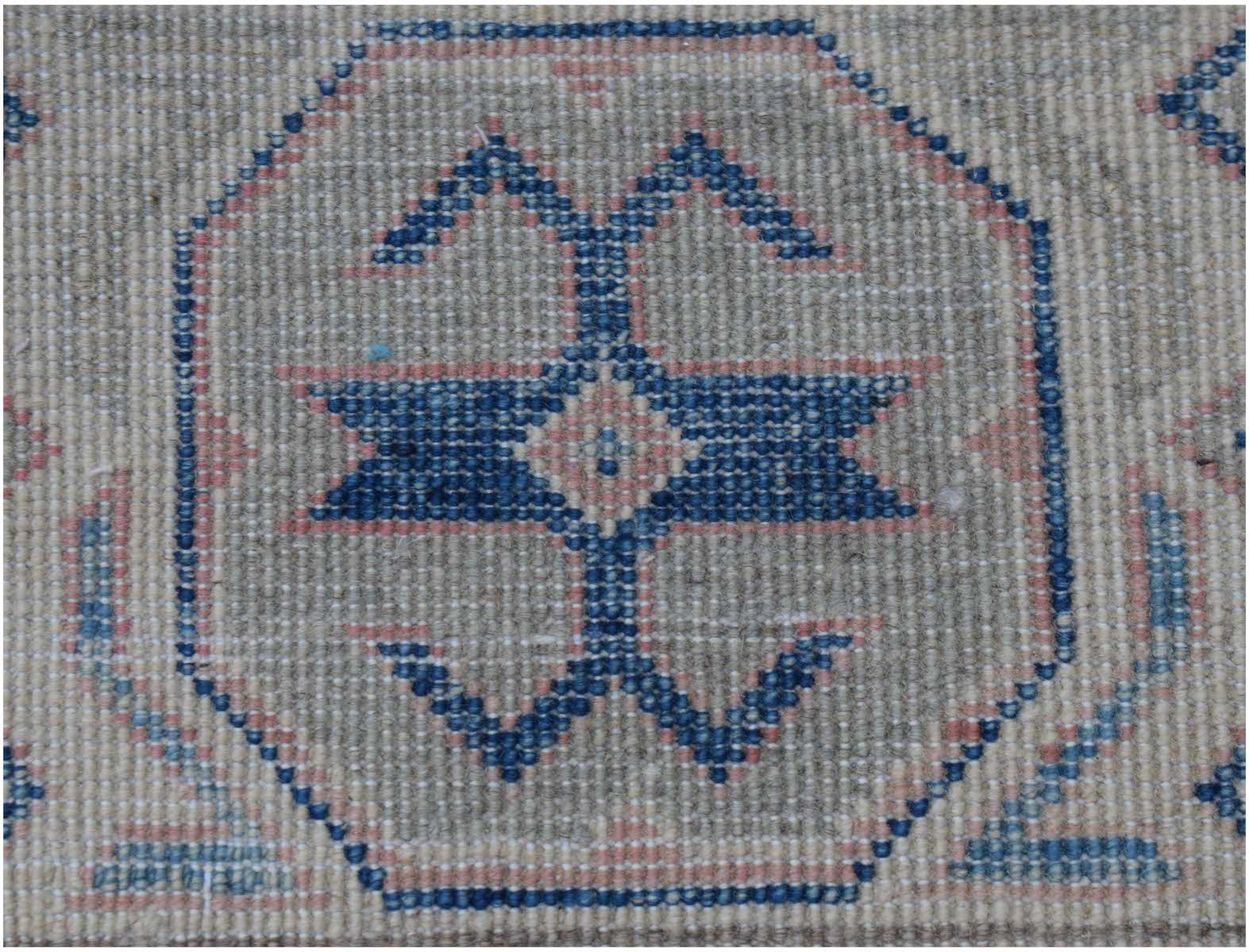 A handmade Afghan Kazakh rug featuring a central blue geometric motif on a light textured background.