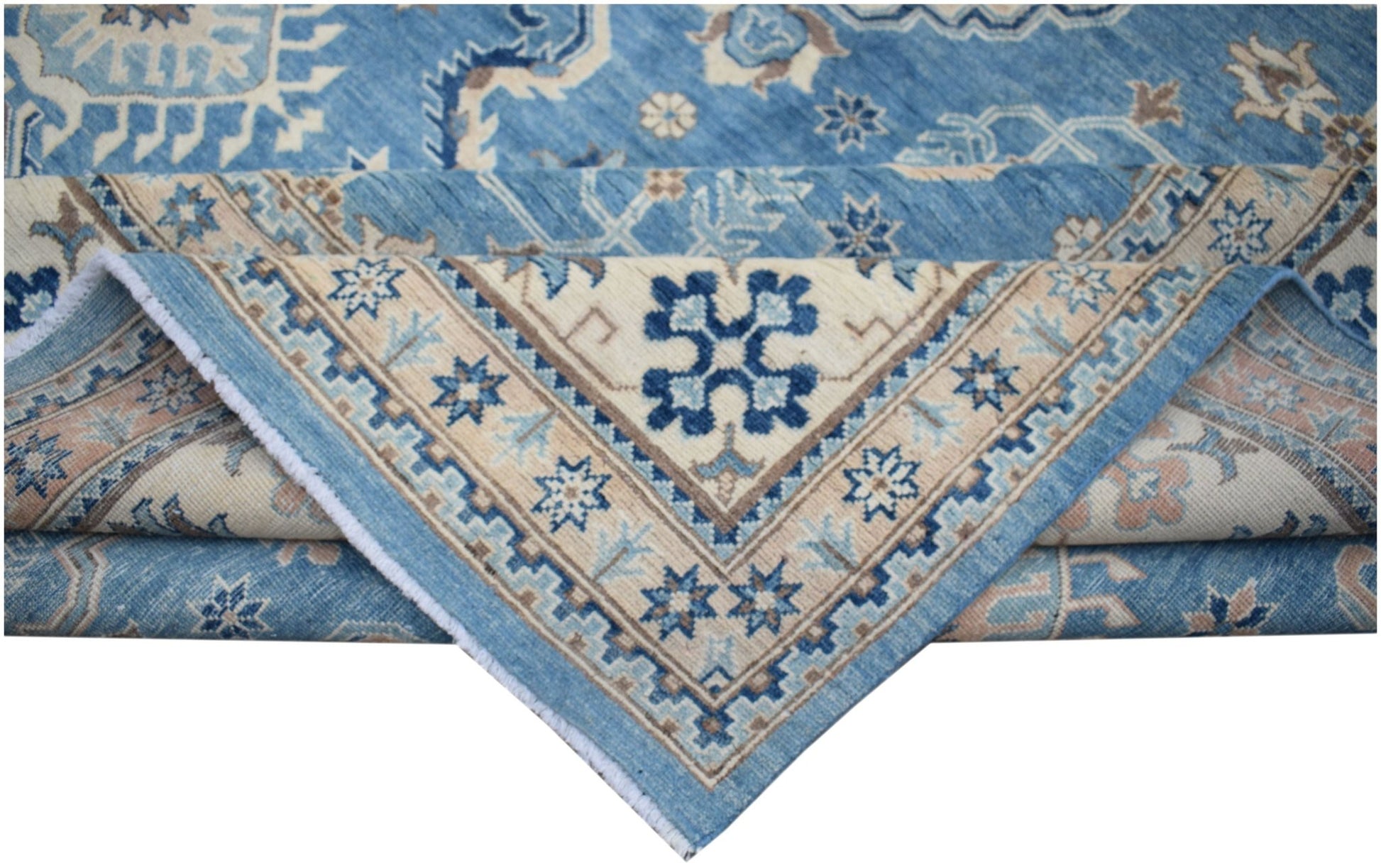 A handmade Afghan Kazakh rug featuring a blue and beige geometric pattern with a folded corner.