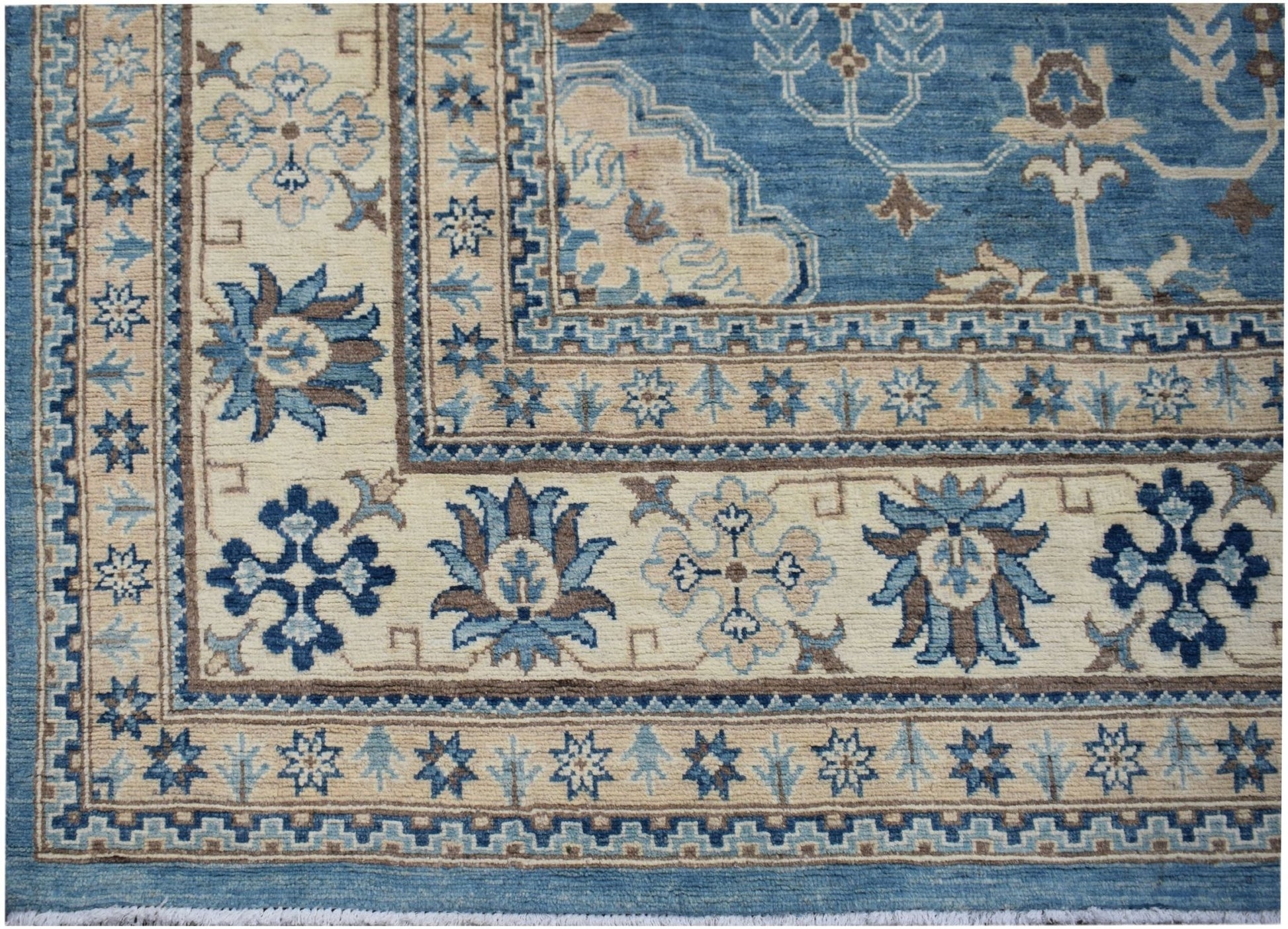 A handmade Afghan Kazakh rug featuring a blue and beige floral pattern with a geometric border.