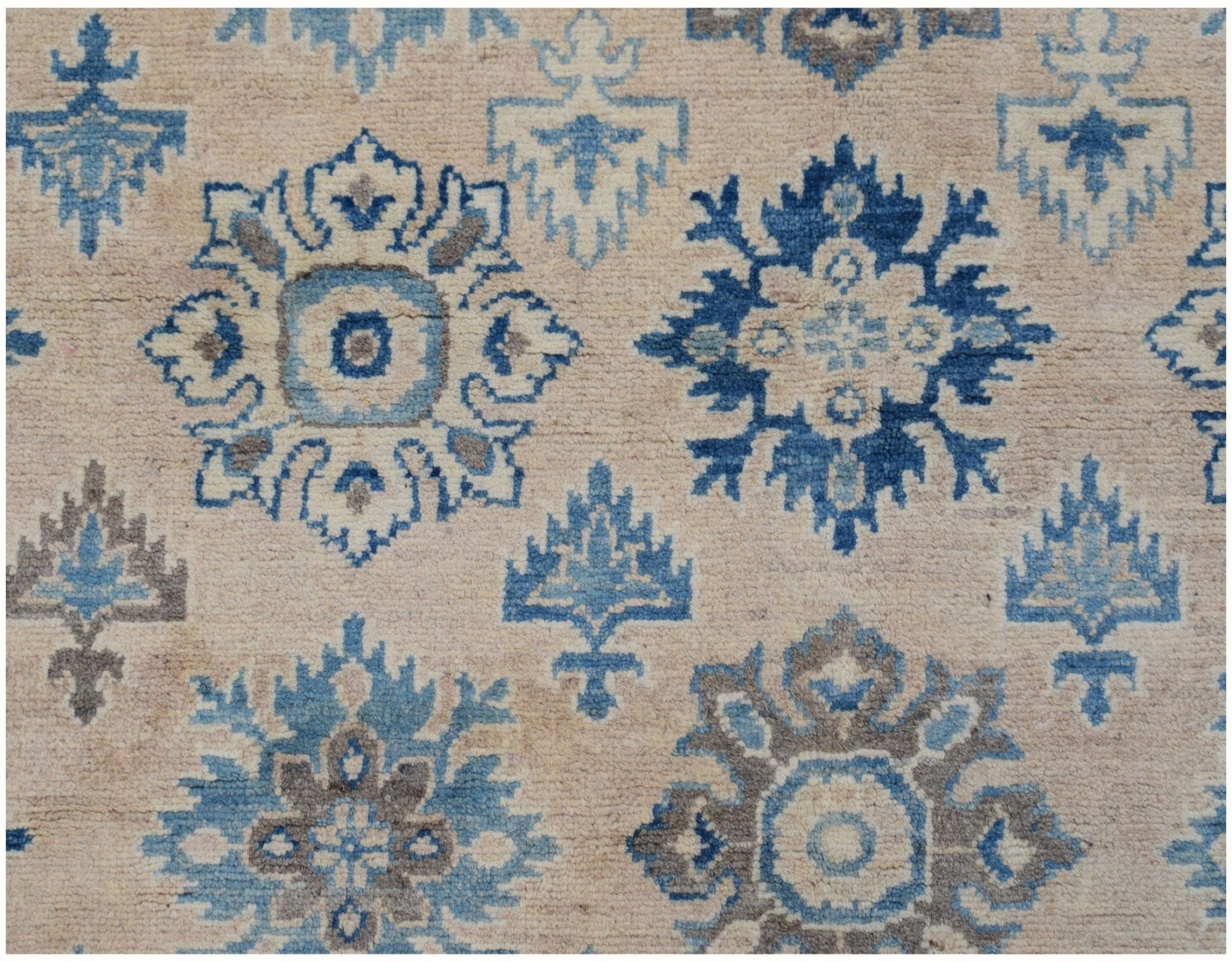 Handmade Afghan Kazakh wool rug featuring a repeating blue and grey floral pattern on a beige base.